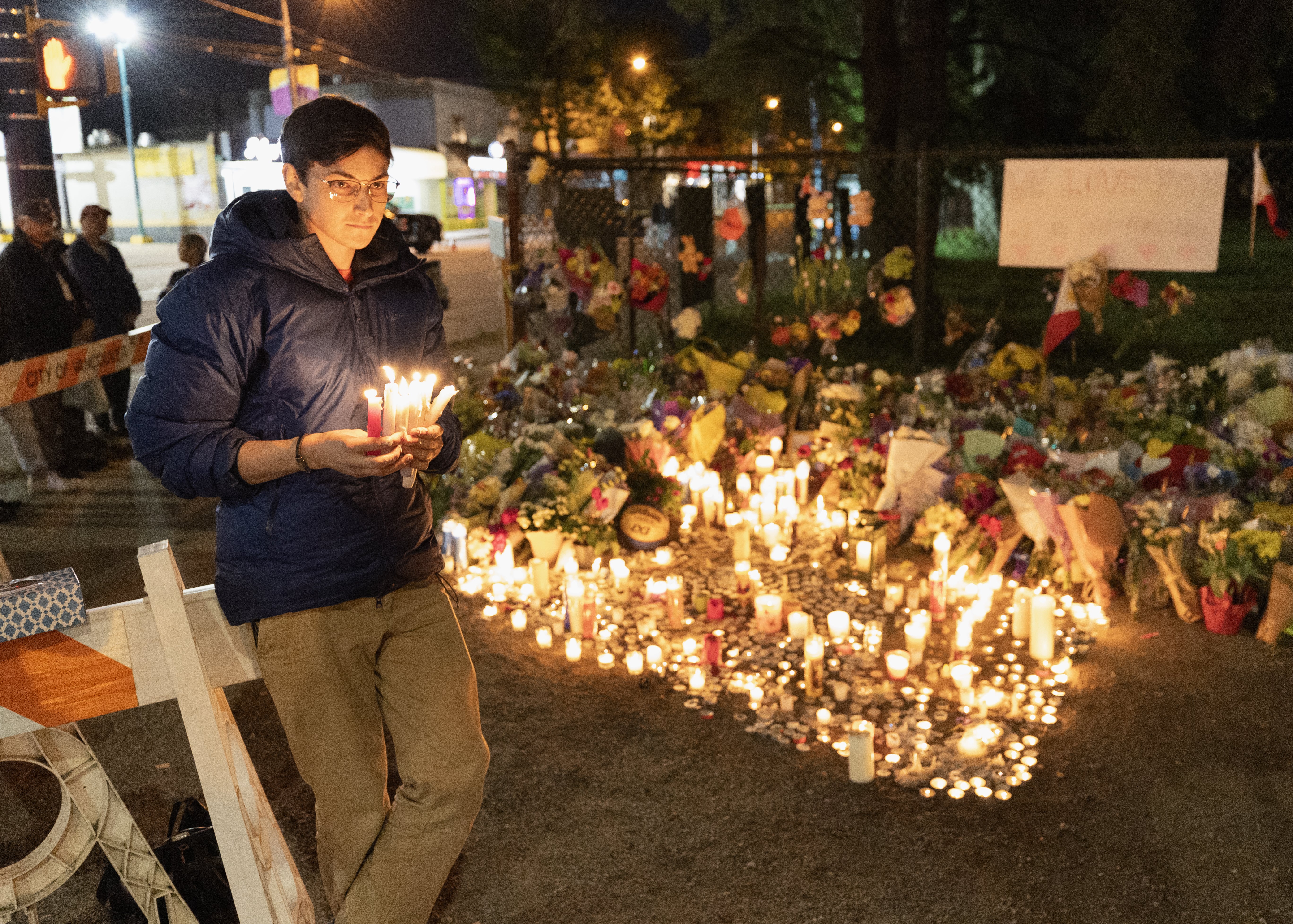 A person is seen holding candles for people attending the candlelight vigil