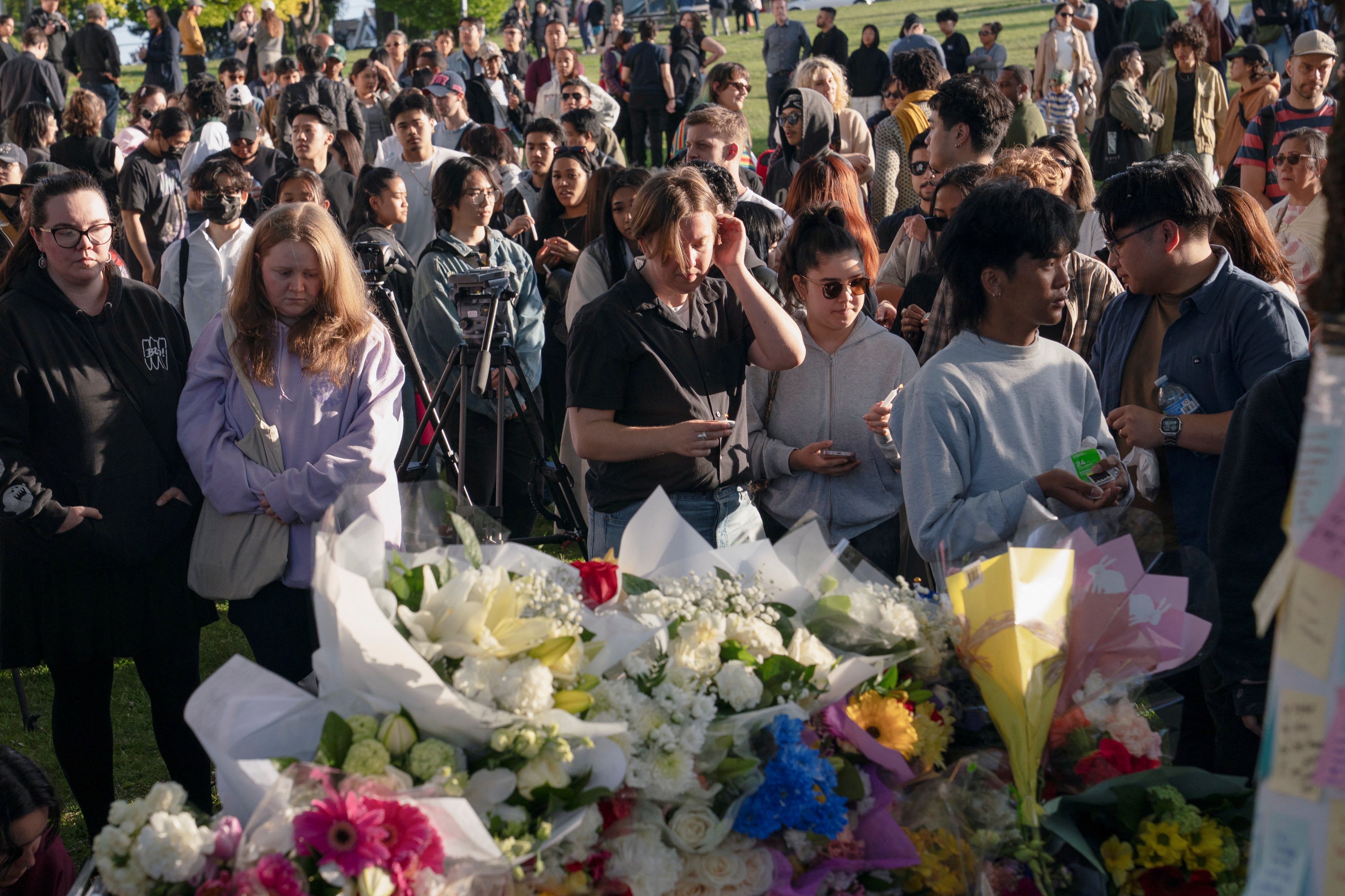 Attendees pay tribute during a community gathering at Kensington Park to mourn the day after a vehicle was driven into a crowd at a Filipino community festival