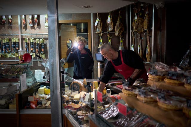 <p>Shop workers use their phone light to select and save some food, during the major power outage in Barcelona</p>