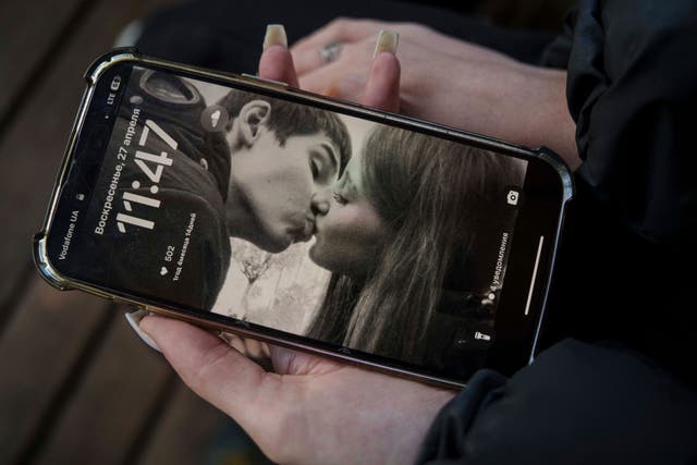 <p>Alyona Zavadska, 16, checks a photo of herself with boyfriend Danylo Khudia, 17, killed in a Russian strike along with his parents, Viktoria and Oleh Khudia on April 24, during a farewell ceremony at the crematorium in Kyiv, Ukraine, on Sunday, April 27, 2025. (AP Photo/Evgeniy Maloletka)</p>