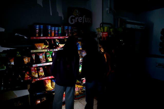 <p>Customers use their mobile phone torches inside a supermarket in downtown Barcelona</p>