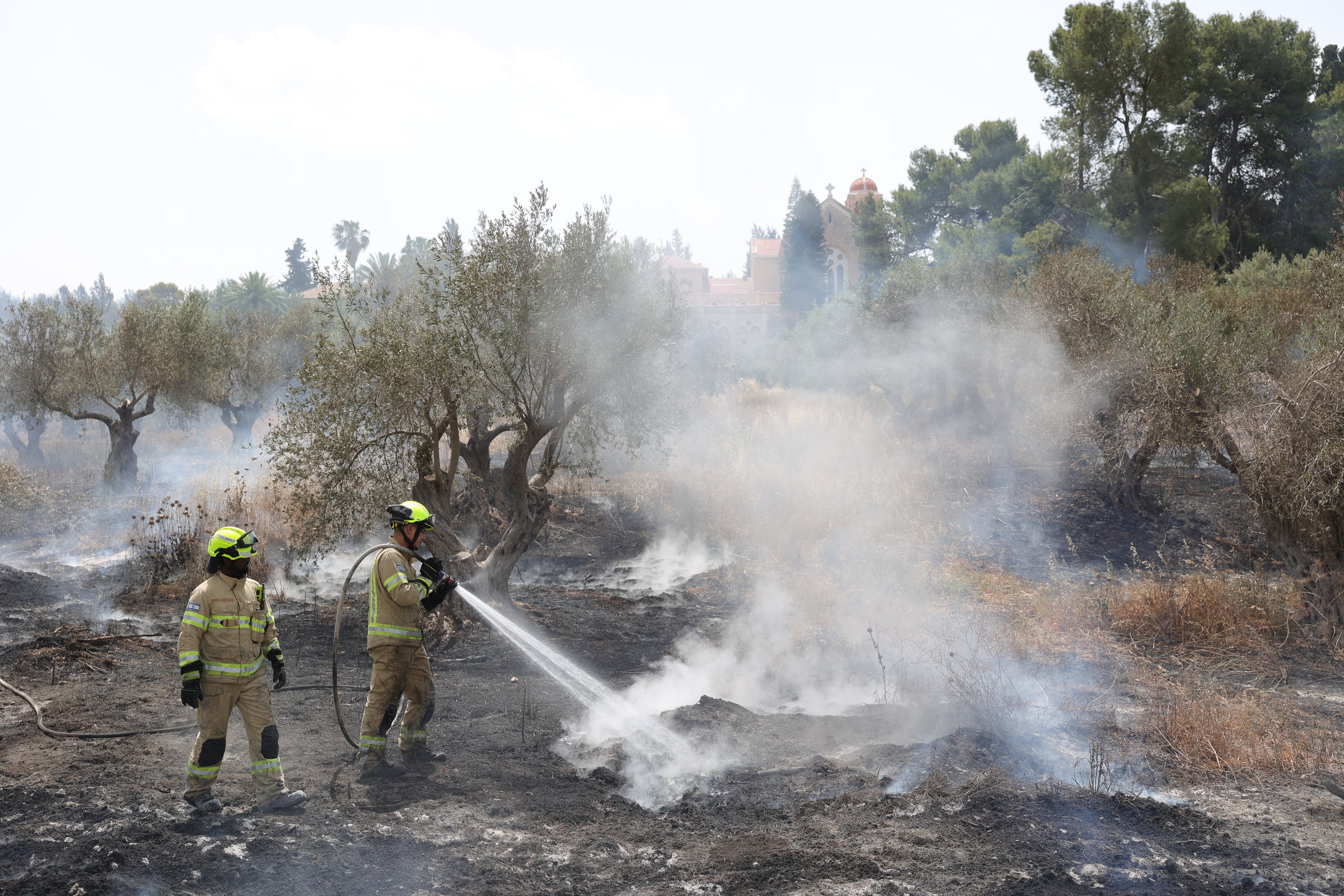 Israeli firefighters work to extinguish a fire burning near Latrun monastery on Thursday