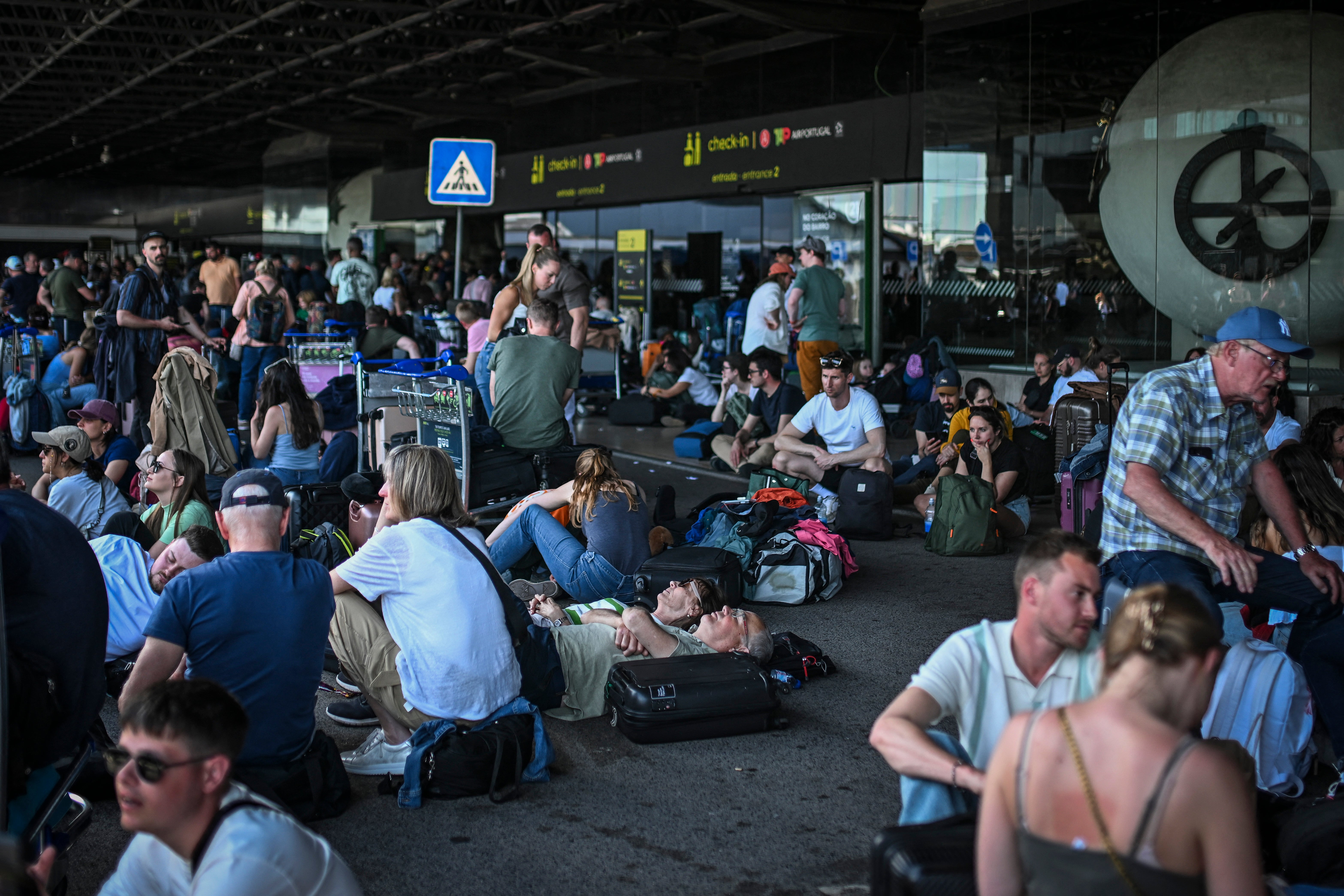 People with their luggage wait outside Humberto Delgado airport following a general electricity shutdown in Lisbon on April 28, 2025