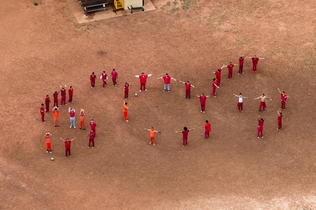 <p>Venezuelan detainees forming the letters 'SOS' with their bodies in the courtyard at the Bluebonnet Detention Facility in Anson, Texas, on Monday April 28 2025</p>
