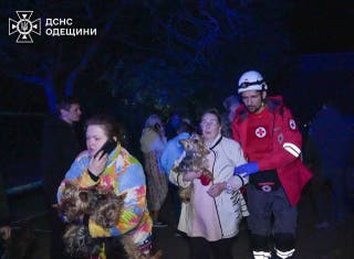 A medical worker evacuates residents from an apartment building damaged during a Russian drone strike in Odesa overnight