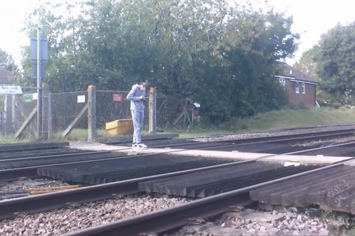 Distracted teenager stops on train tracks to check phone in shocking CCTV footage