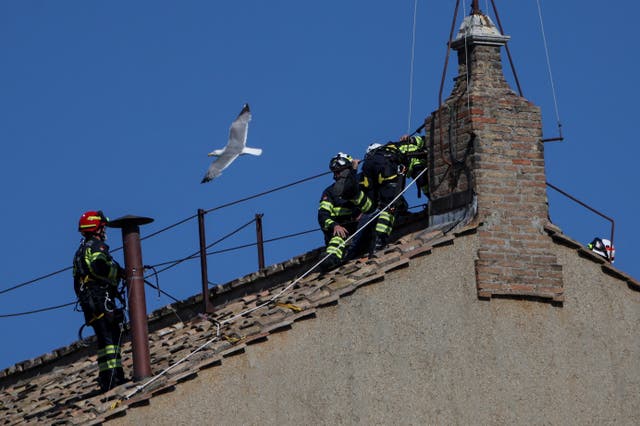 <p>A seagull flies near firefighters as they work on the roof of the Sistine Chapel to set a chimney, ahead of the conclave, at the Vatican May 2, 2025. REUTERS/Stoyan Nenov</p>