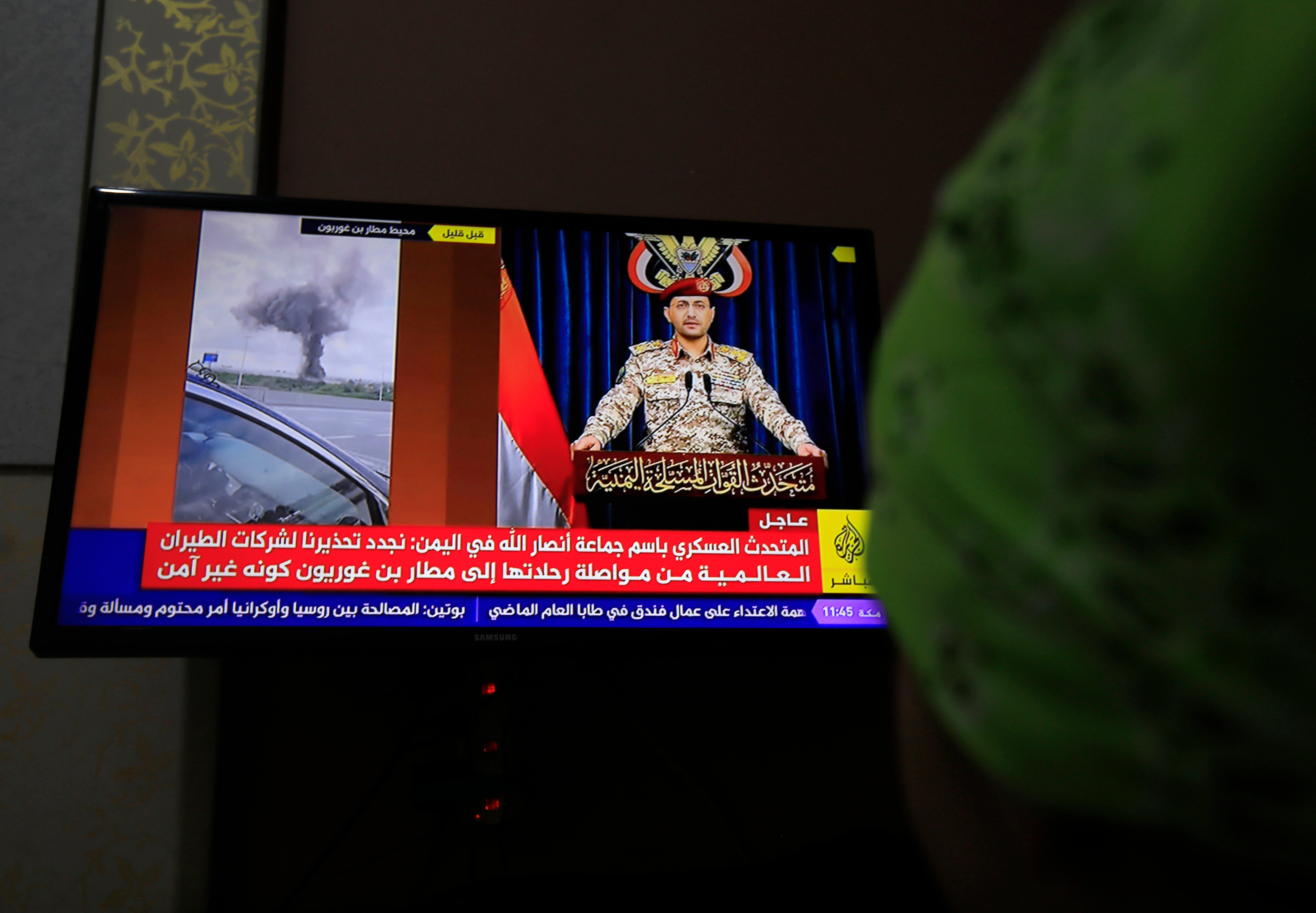 A person watches Houthi military spokesman Yahya Sarea delivering a televised statement about a missile attack on Israel's Ben Gurion airport, in Sana'a, Yemen, 04 May 2025