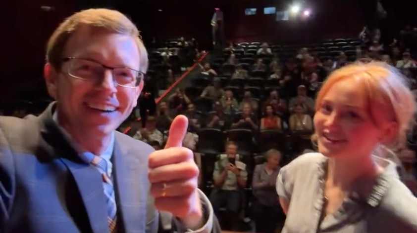 Congressman Dusty Johnson smiles and gives the thumbs up next to a woman named Samantha as they unveil a statue of Donald Trump to a half-empty auditorium in Rapid City, South Dakota