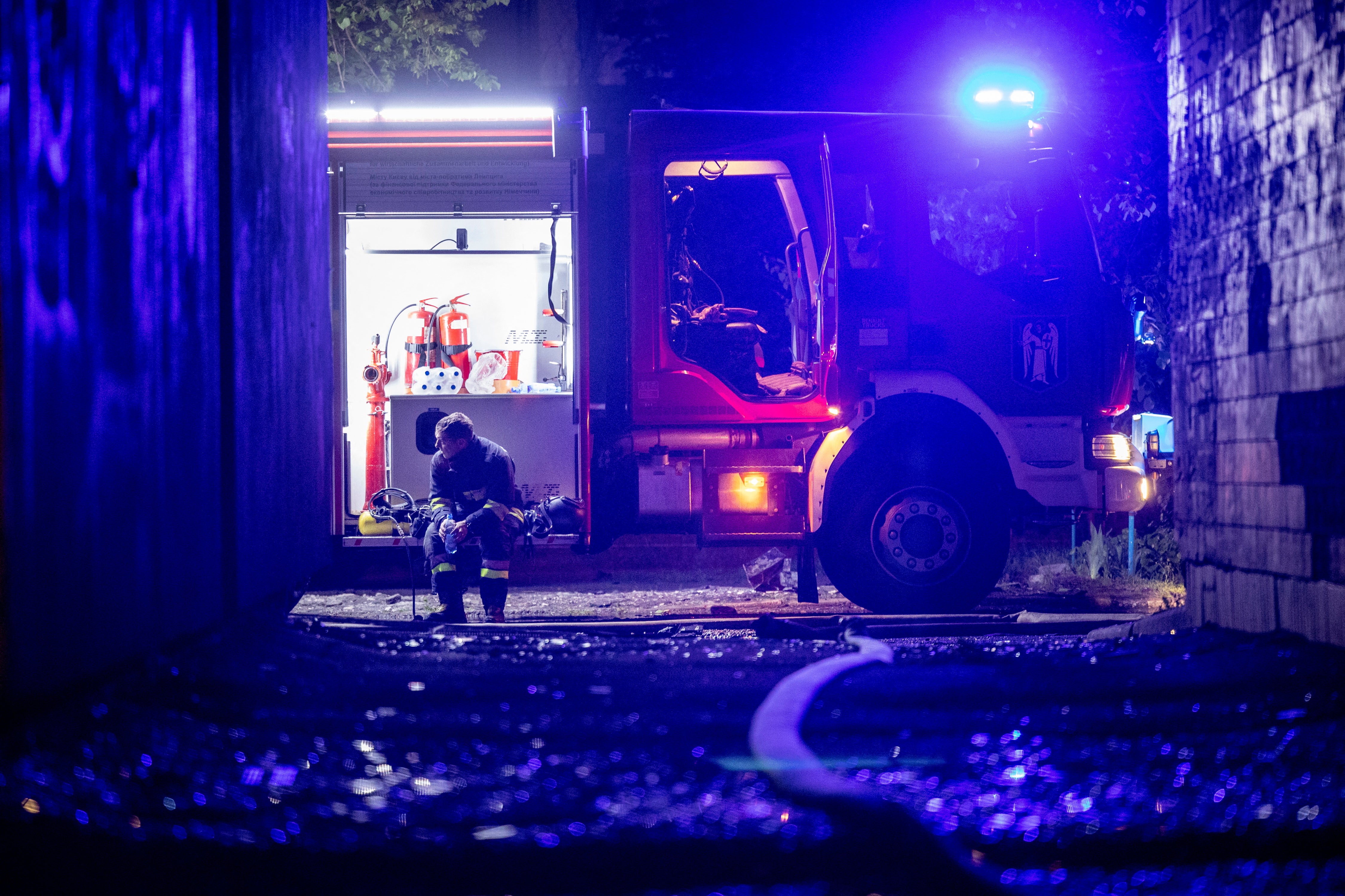 An emergency worker rests after extinguishing a fire in an apartment building following a Russian drone attack in Kyiv on Sunday