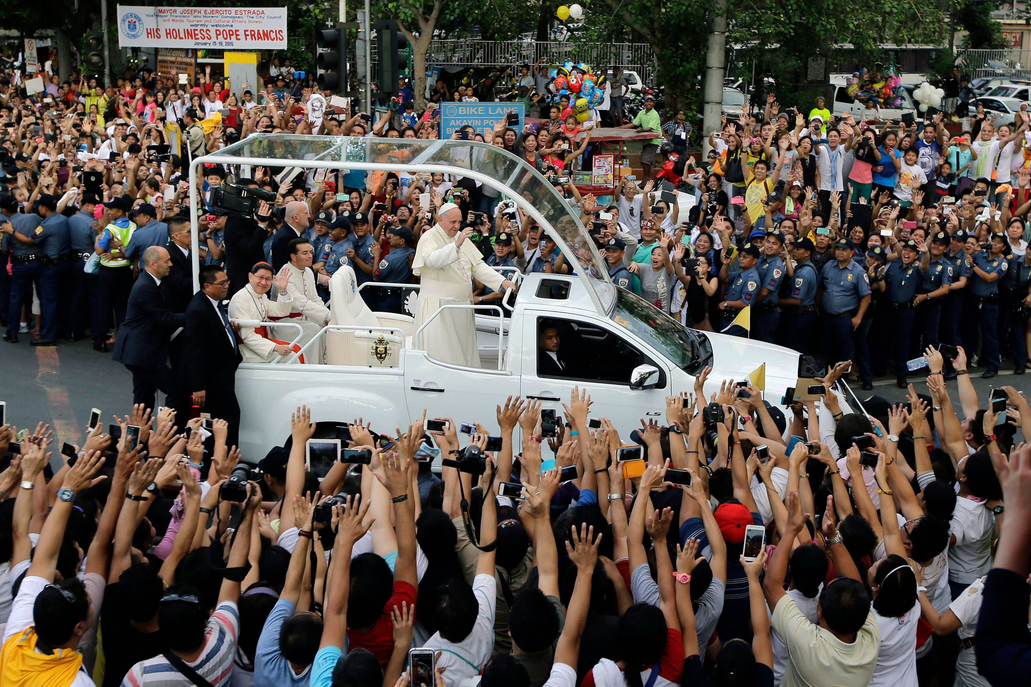 Pope Francis waves to onlookers from his popemobile as his motorcade passes by on the way to another "Meeting With Families" at the Mall of Asia Arena in Manila, Philippines