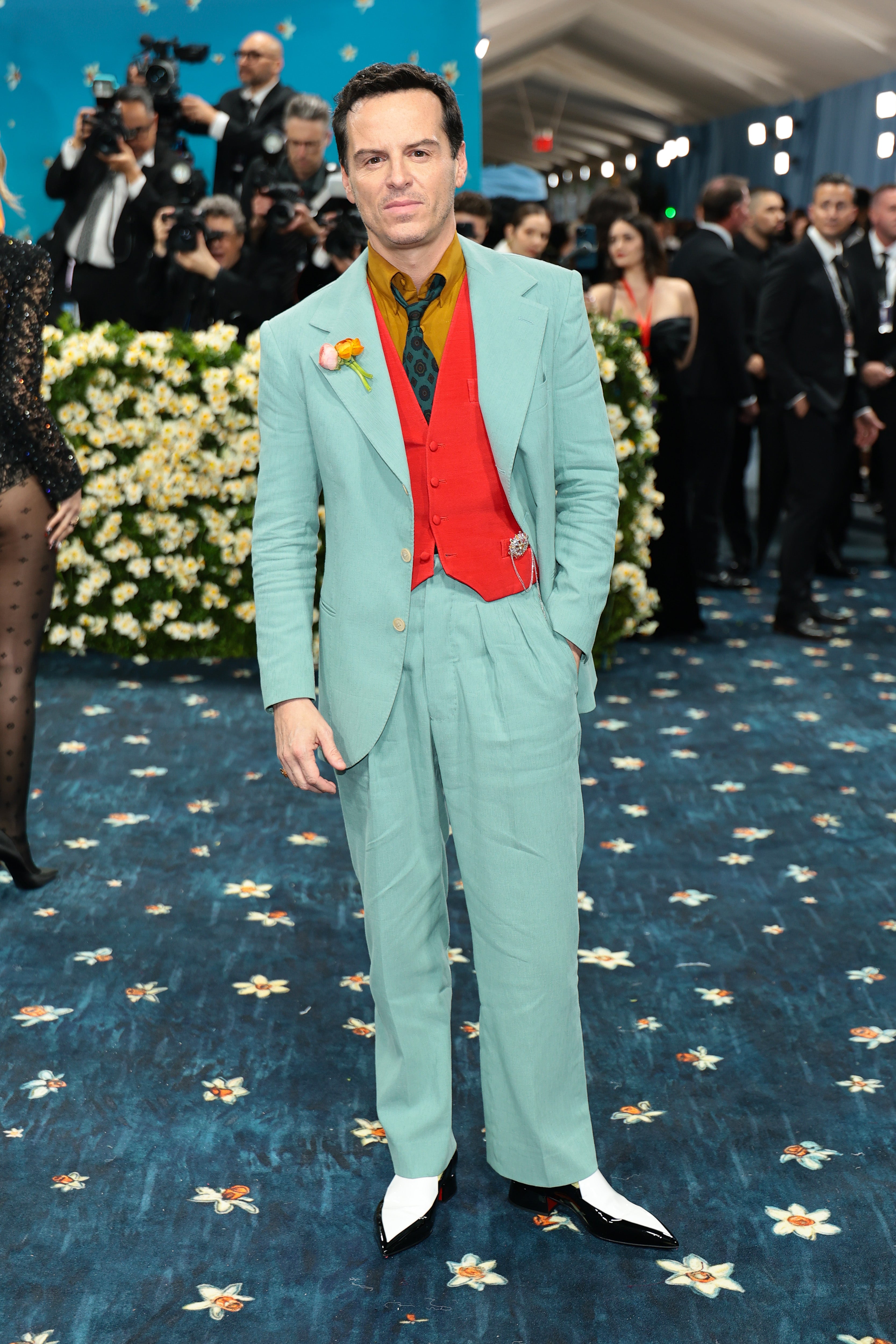 Andrew Scott attended the Met Gala in a teal blue suit with a red vest, a mustard-colored shirt, and pointed-toe white shoes. The suit looked to be fashioned from a thin, wrinkly material and made him look a bit disheveled