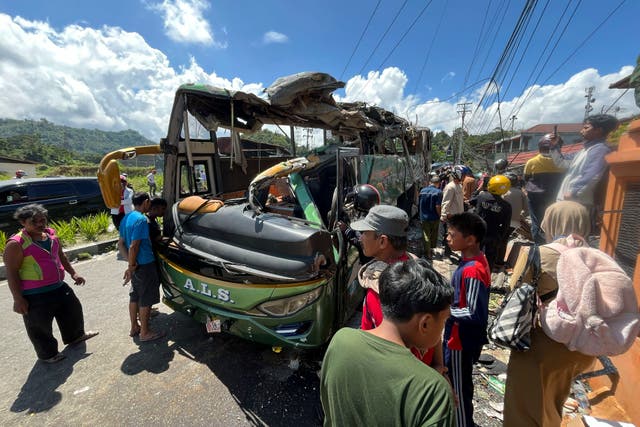 <p>People inspect the wreckage of a bus after it sped out of control on a downhill road and overturned in Padang Panjang, West Sumatra</p>