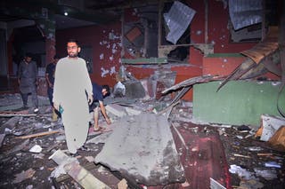 Local residents examine a building damaged from a suspected Indian missile attack near Muzaffarabad, the capital of Pakistan controlled Kashmir