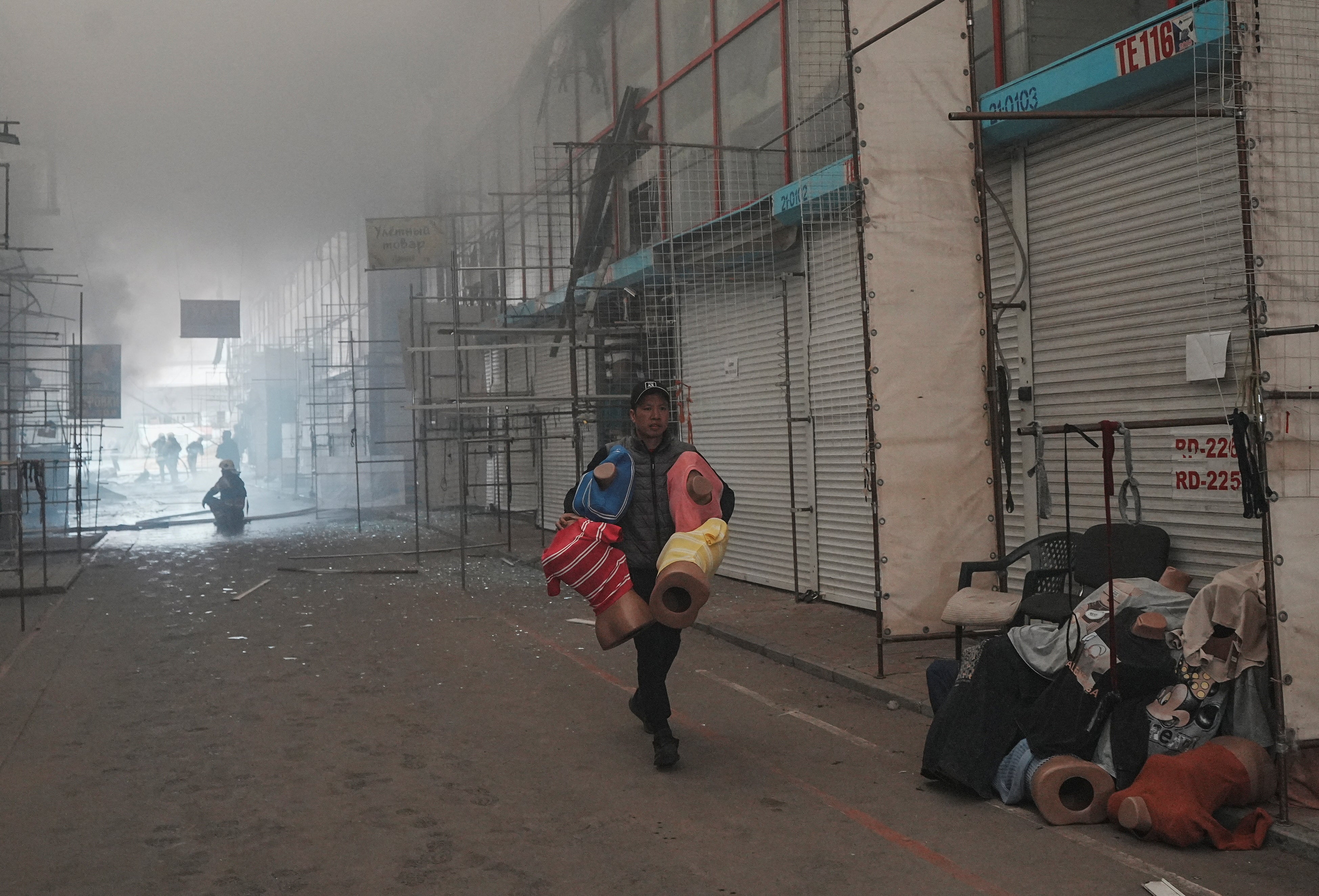 A vendor carries his goods, saving them from a fire at site of Barabashovo market