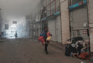 A vendor carries his goods, saving them from a fire at site of Barabashovo market