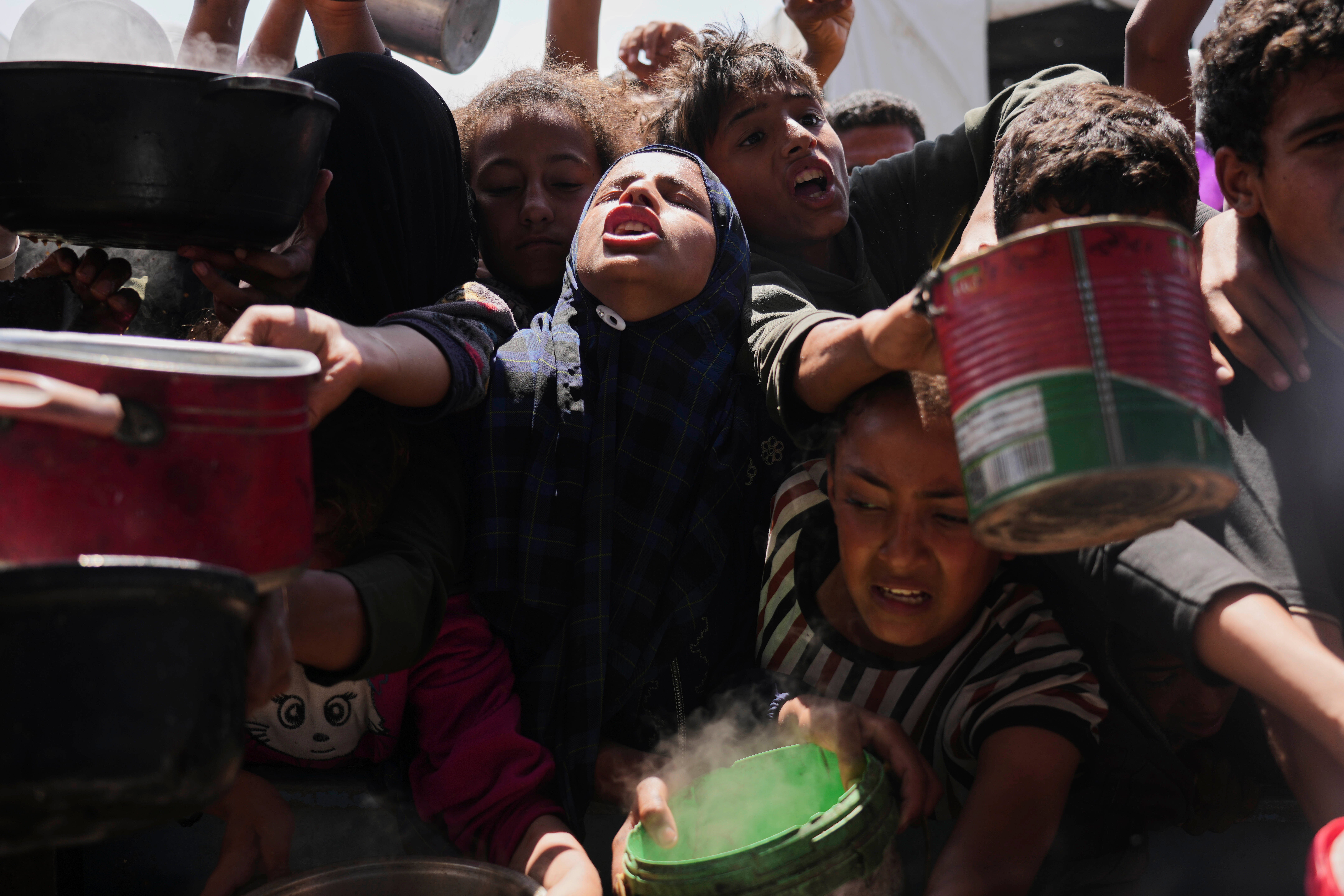 Palestinians struggle to get donated food at a community kitchen in Khan Younis on May 5