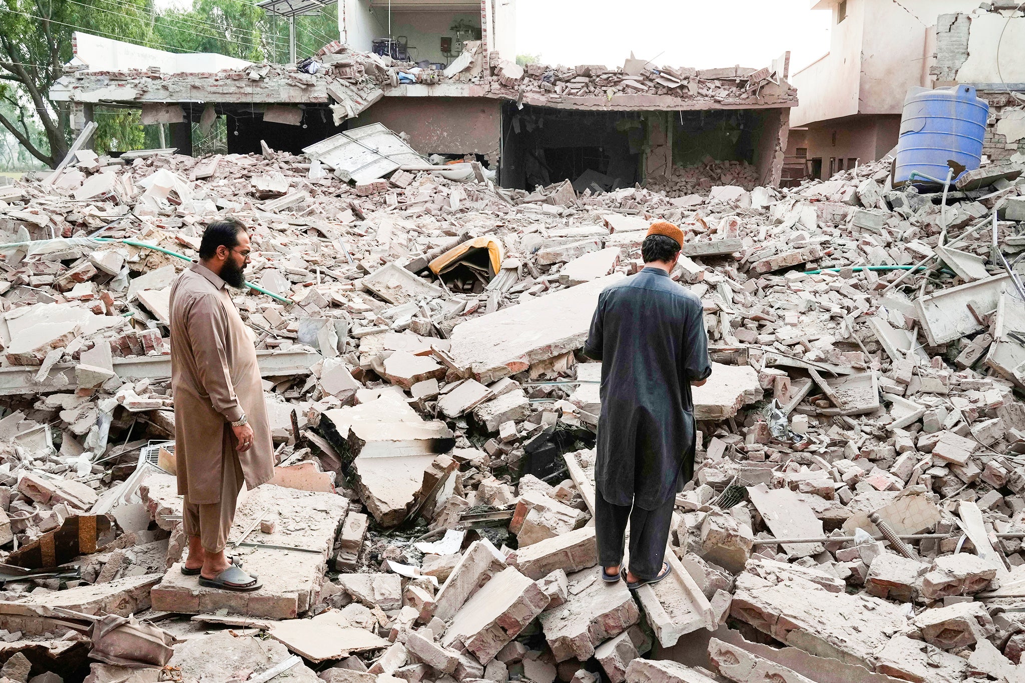 Local residents walk through the rubble of a building damaged by suspected Indian missile attack, in Muridke, a town in Pakistan's Punjab province, Wednesday, May 7, 2025. (AP Photo/K.M. Chaudary)