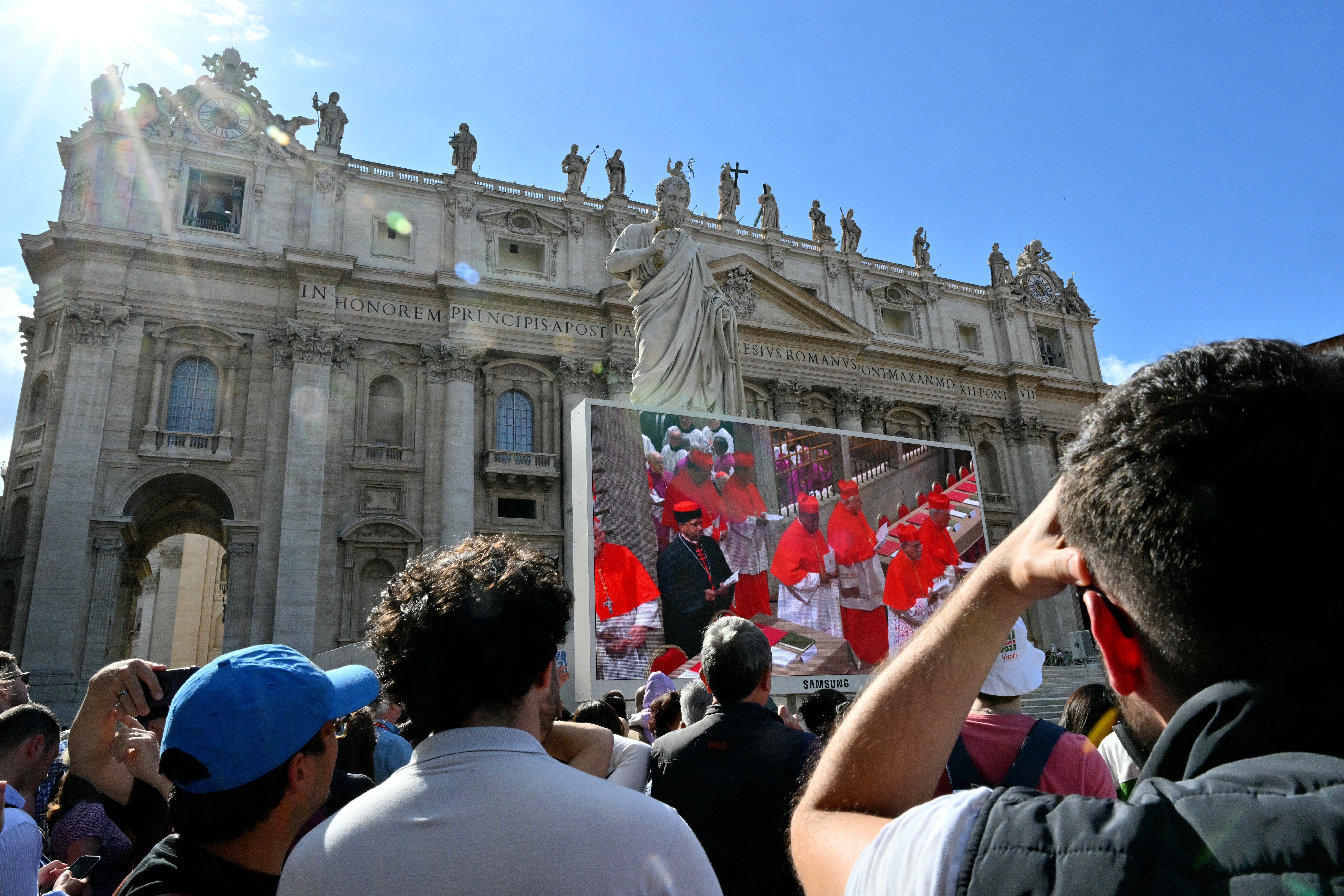 Faithful watch giant screen displaying images of the procession of cardinals to the Sistine chapel