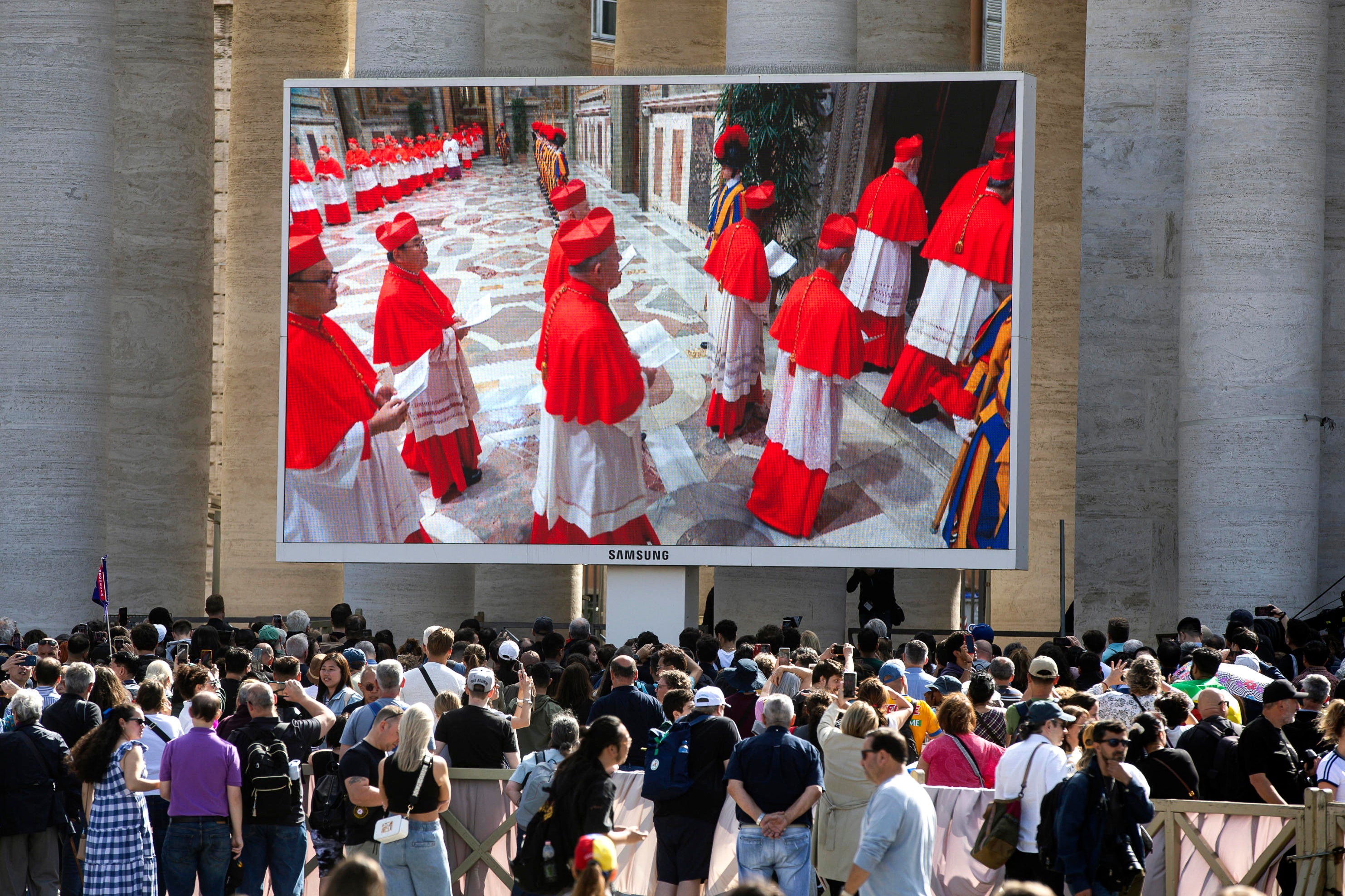 Faithful watch the procession of cardinals to the Sistine chapel on a giant screen installed in St Peter's Square