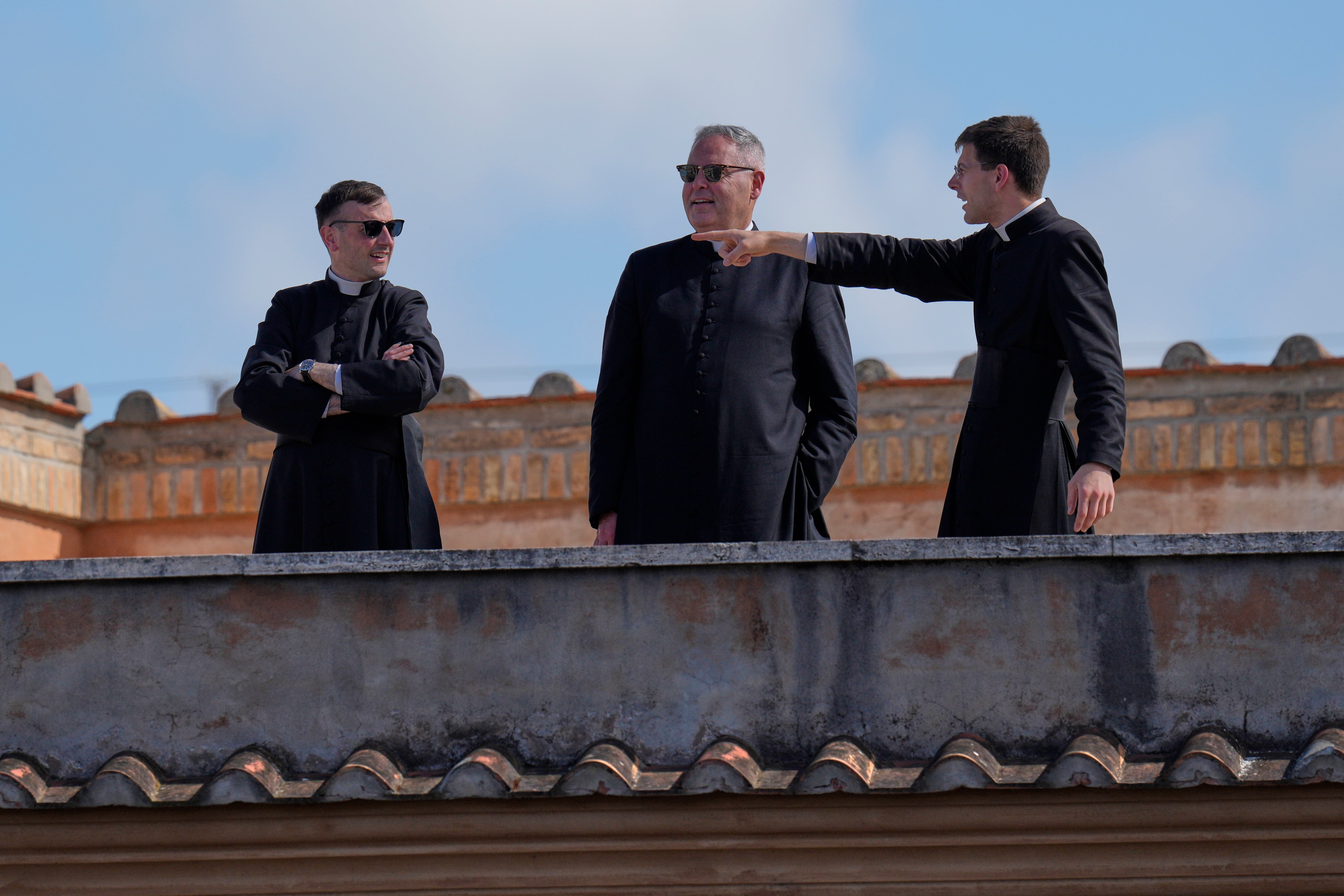 Priests stand on a rooftop balcony overlooking St Peter's Basilica