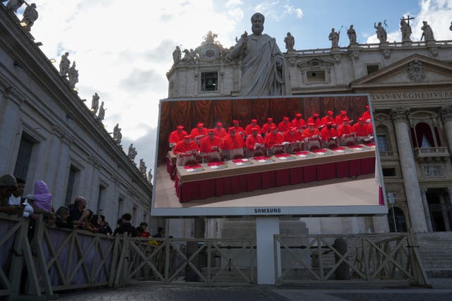 A giant screen in St Peter’s Basilica shows cardinals inside the Sistine Chapel during the conclave (Alessandra Tarantino/AP)