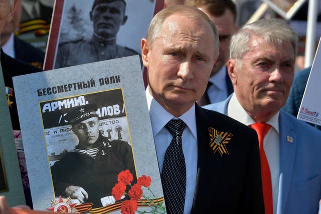 <p>Vladimir Putin holds a portrait of his father, a veteran of the Second World War, during Victory Day celebrations in Red Square, in Moscow in 2019</p>