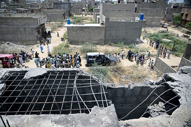 <p>Residents gather as police personnel inspect the site where a drone was reportedly shown in Karachi on 8 May 2025</p>