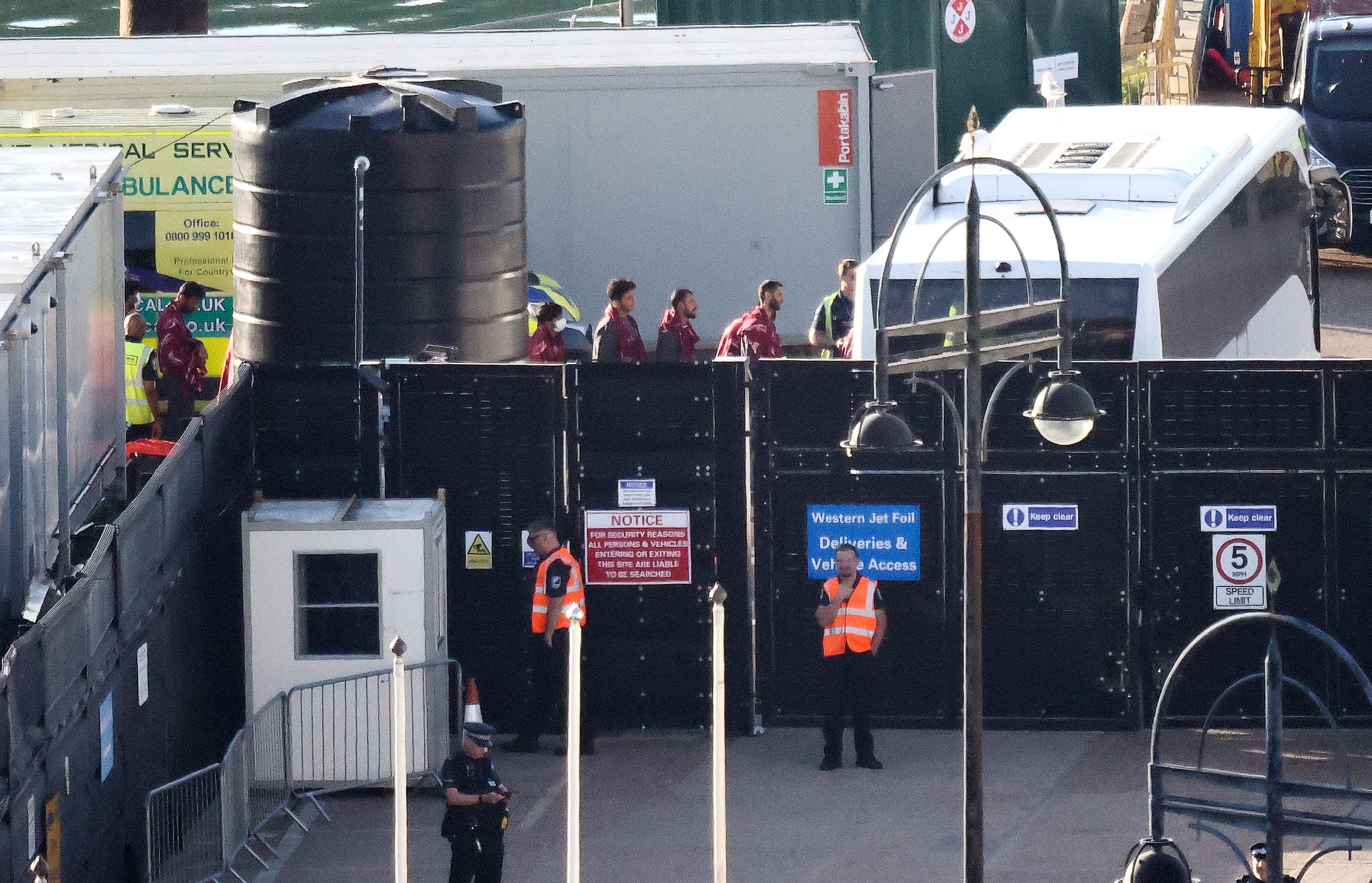 Migrants picked up in the Channel are led to a bus in Dover to take them to Western Jet Foil in August 2023