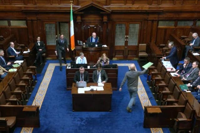 People Before Profit TD Paul Murphy hands Tanaiste Simon Harris a document during Leaders’ Questions on Thursday (Oireachtas TV/Screenshot/PA)