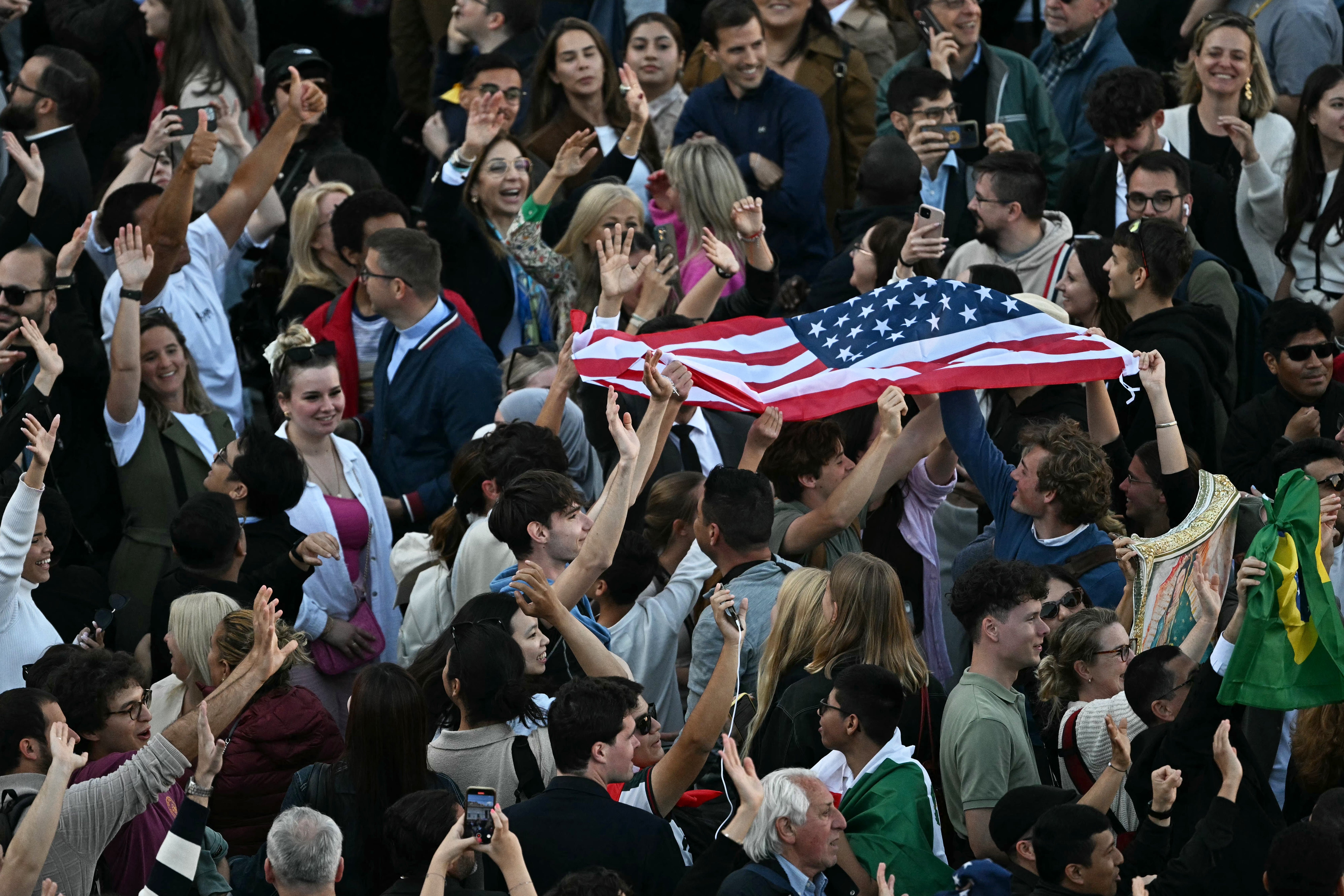 People react with a US flag at St Peter's Square
