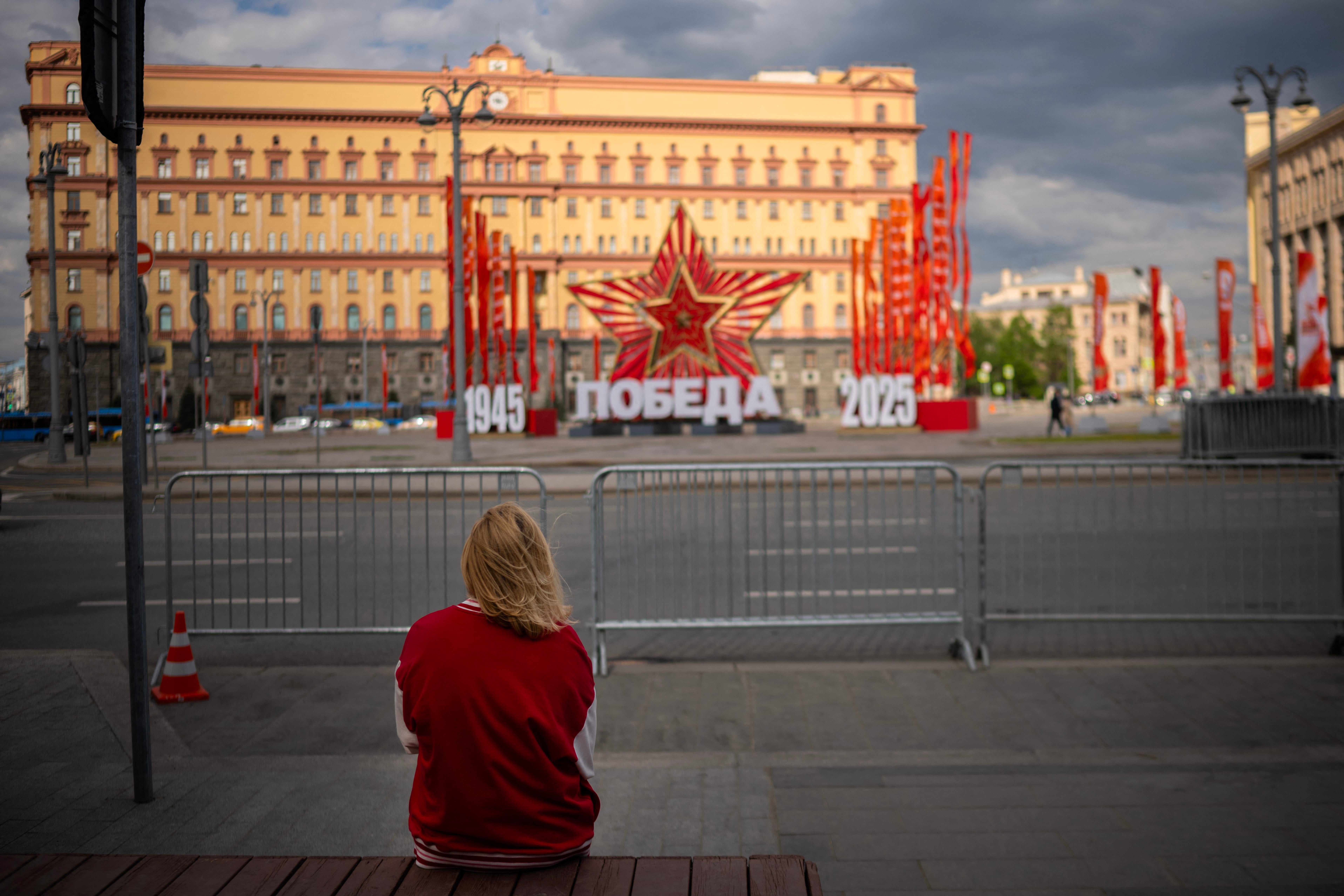 A woman sits on a bench in central Moscow as the FSB security service (former KGB) headquarters and decorations for the Victory Day