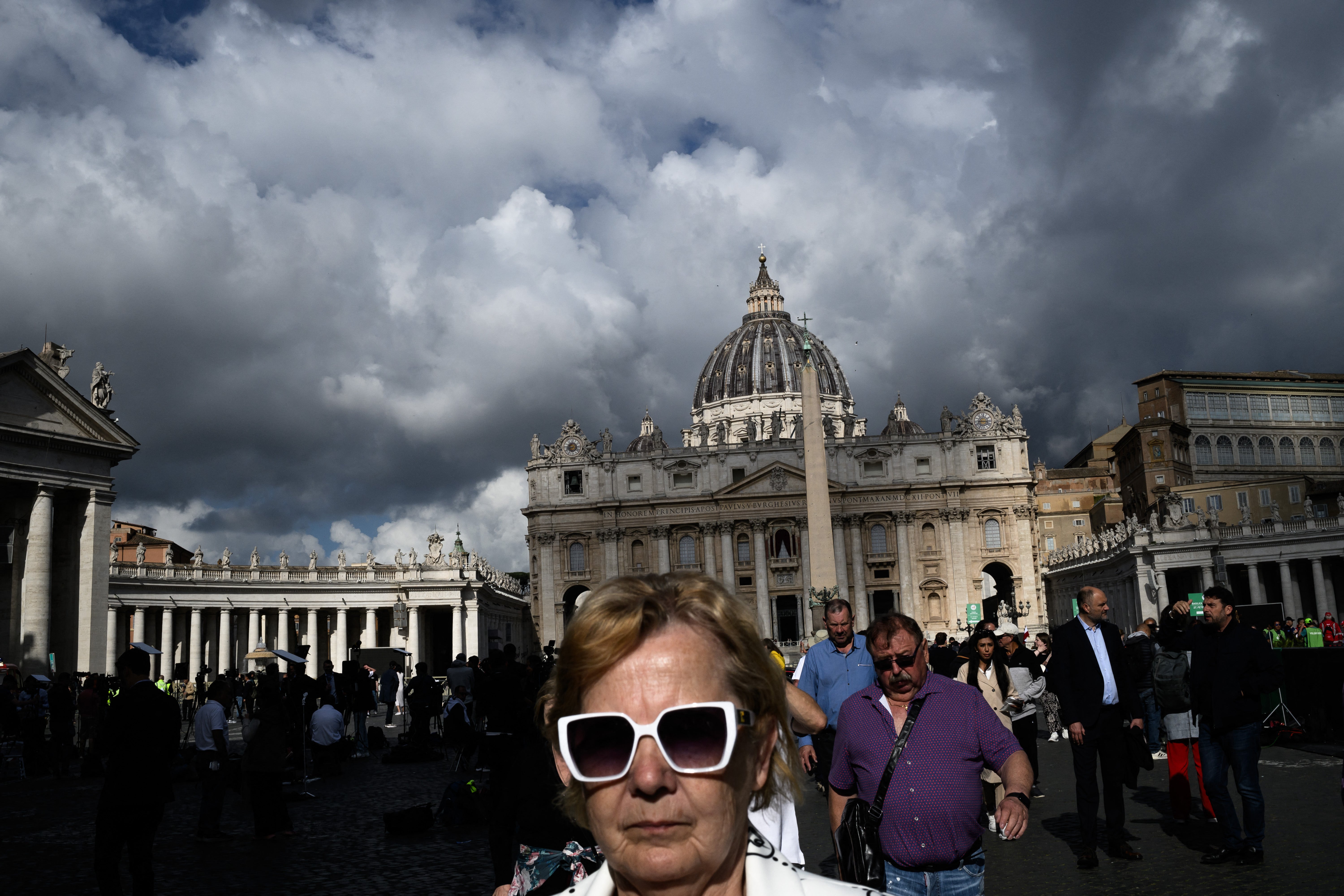 Pedestrians walk near the Vatican with the Saint-Pierre basilica in the background