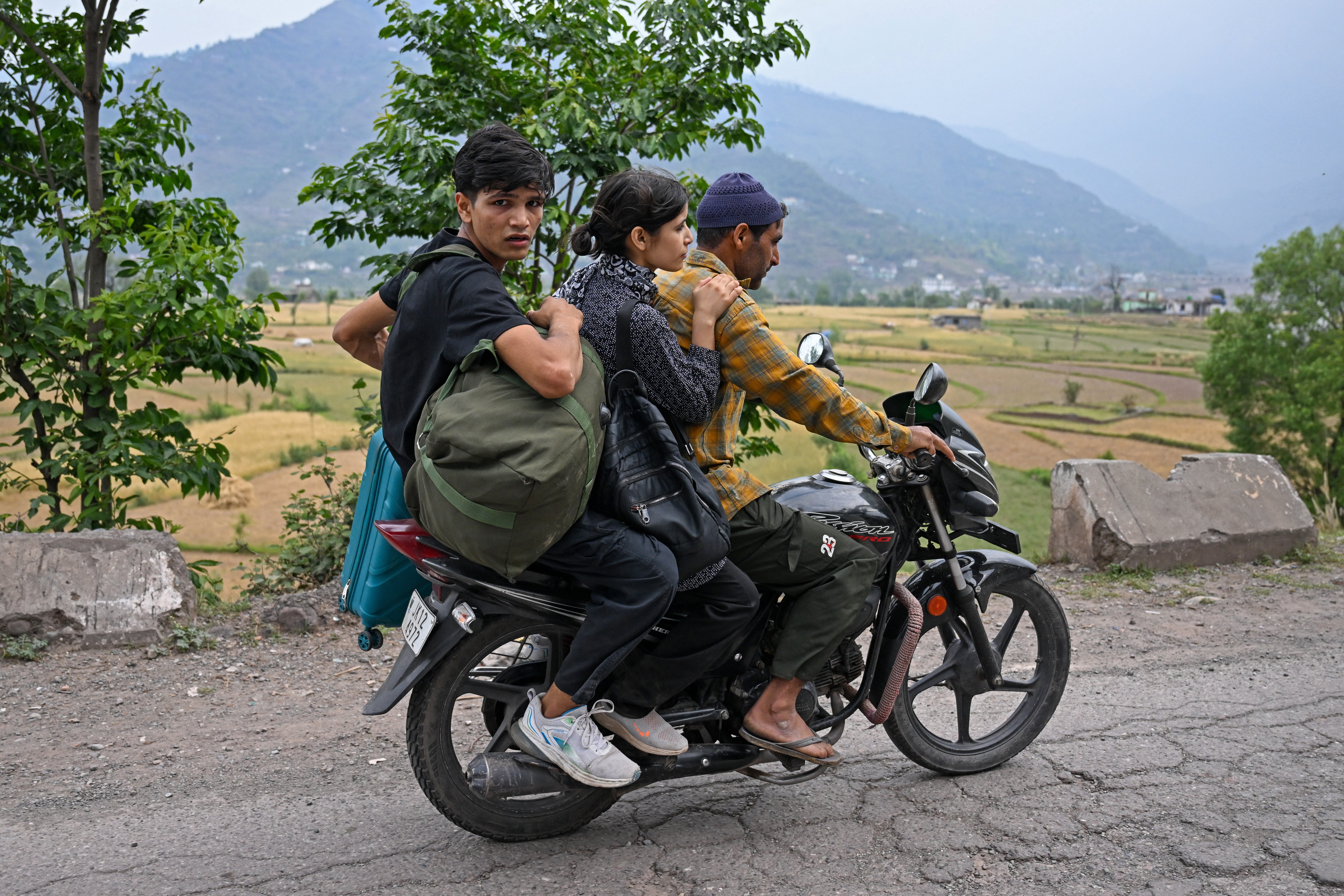 Locals carrying belongings ride a motorbike as they try to escape after heavy artillery shelling