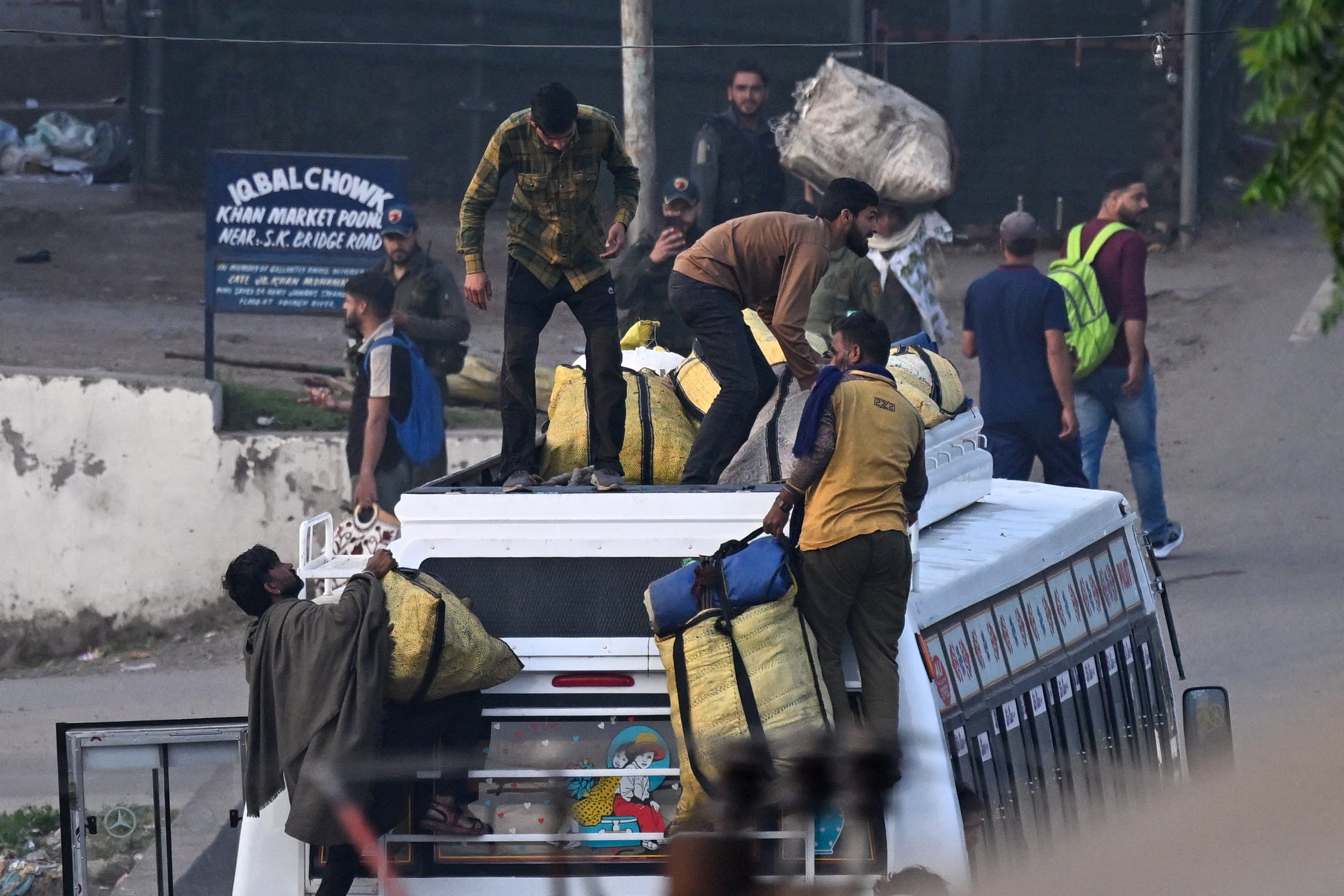 Locals load their belongings on a bus as they try to escape after heavy artillery shelling in the main town of Poonch district in India's Jammu region