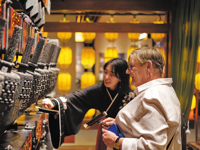 <p>A foreign tourist learns to play bianzhong, or bronze chime bells, at the Oriental Music Cultural Museum in Dalian, Liaoning province, on 3 May</p>