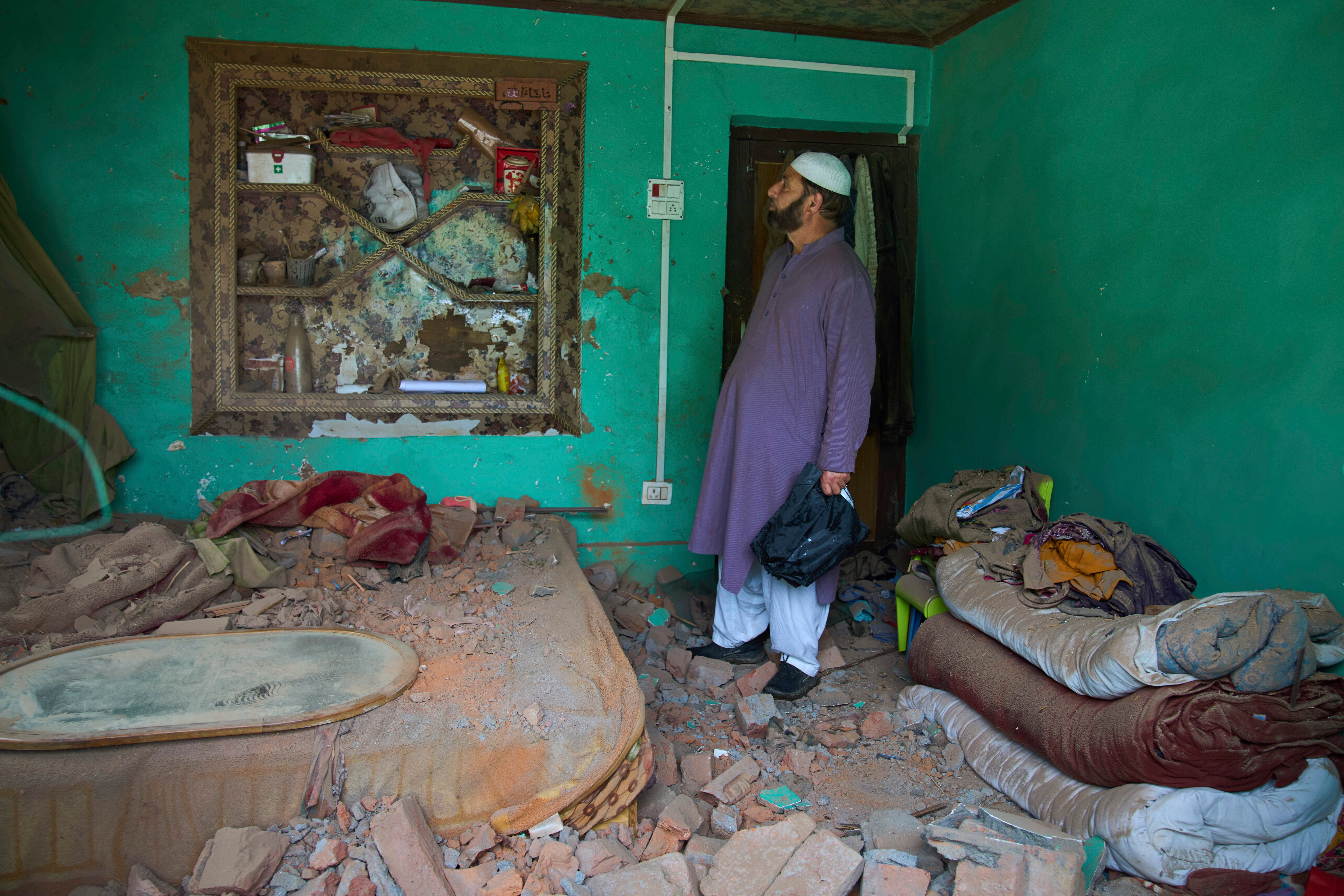 A Kashmiri villager inspects a damaged house after overnight shelling from Pakistan at Gingal village in Uri
