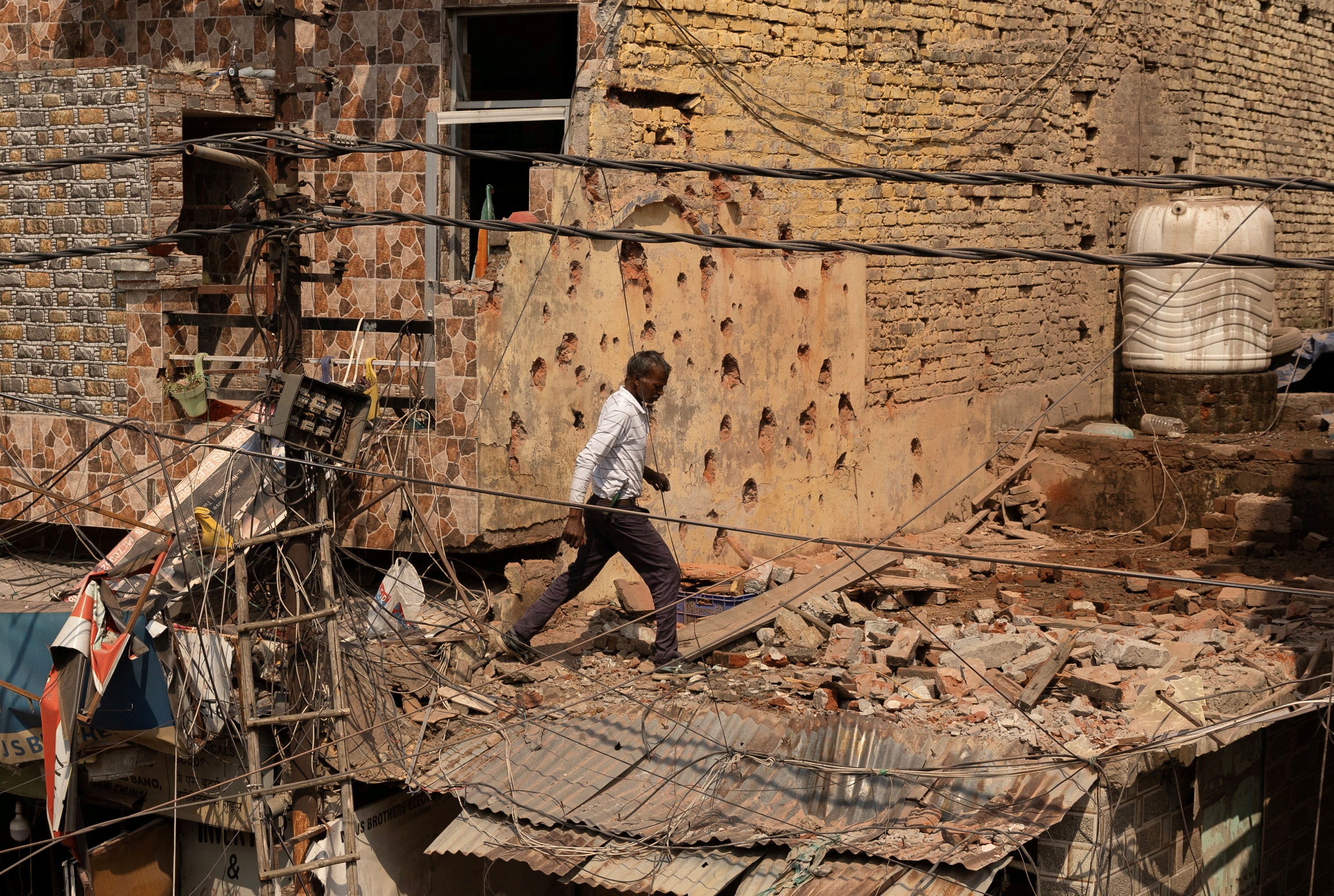 A man walks amid debris on the roof of a damaged house following Pakistan's military operation against India in Rehari, Jammu