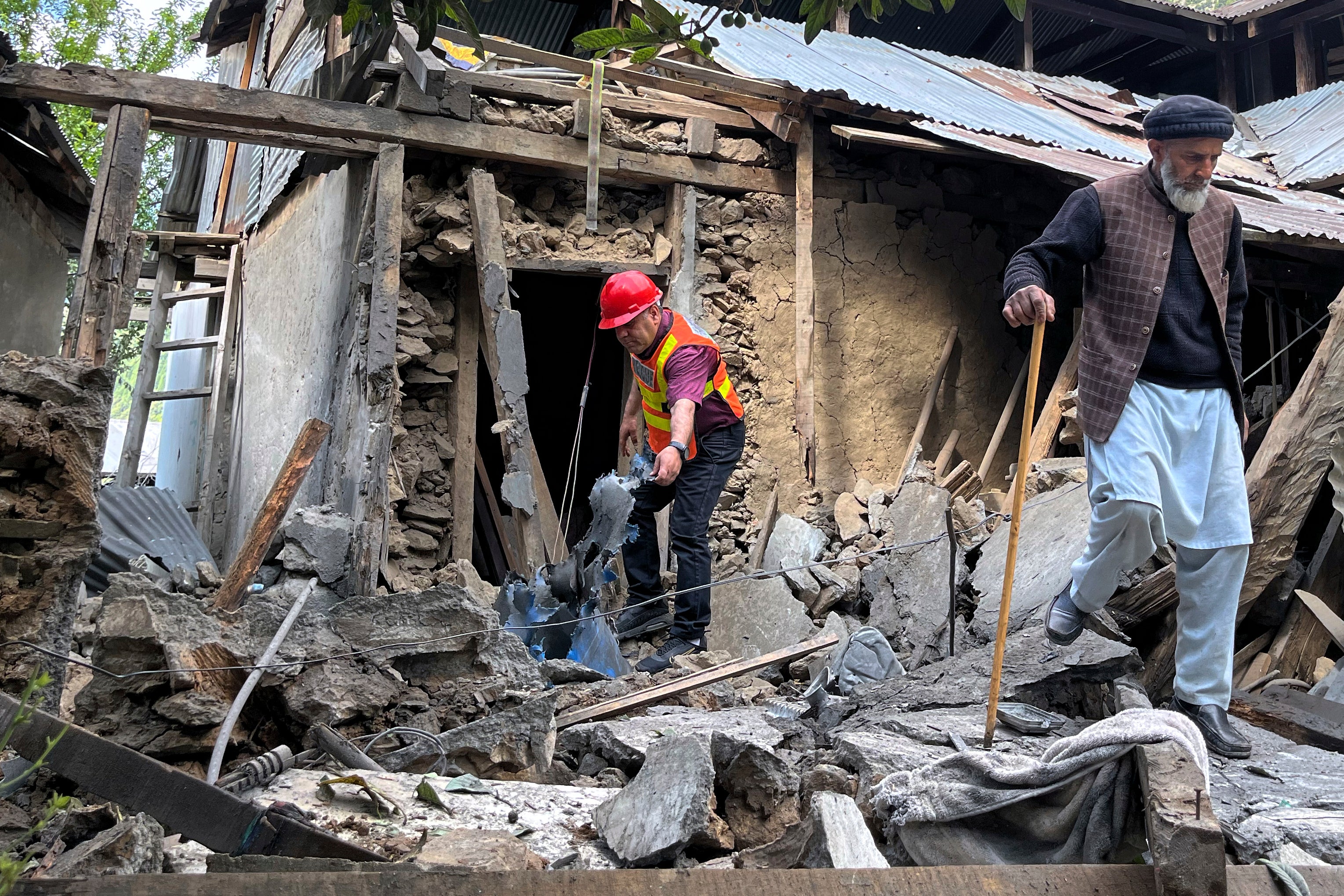 A villager and a rescue worker examine damage to a house caused by Indian shelling in Shah Kot in Pakistan-administered Kashmir