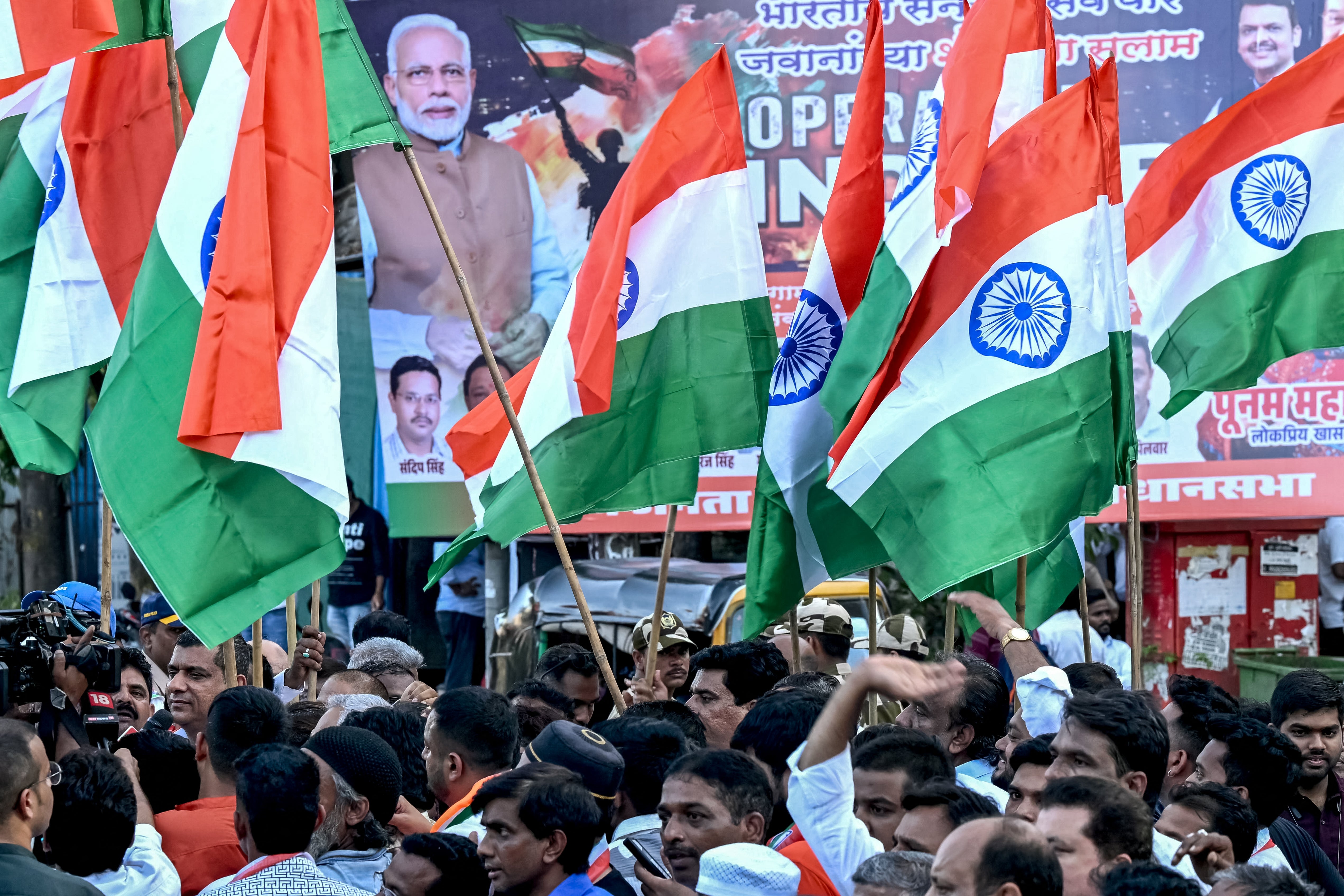 Activists hold the national flag of India in front a banner that praises the Indian defence forces for their military operation, code-named