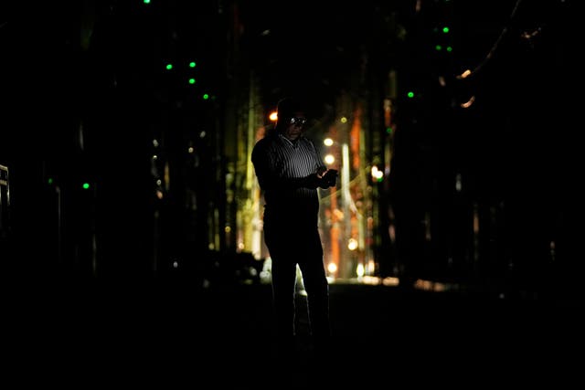 A man checks his mobile phone during a blackout in Jammu (Channi Anand/AP)
