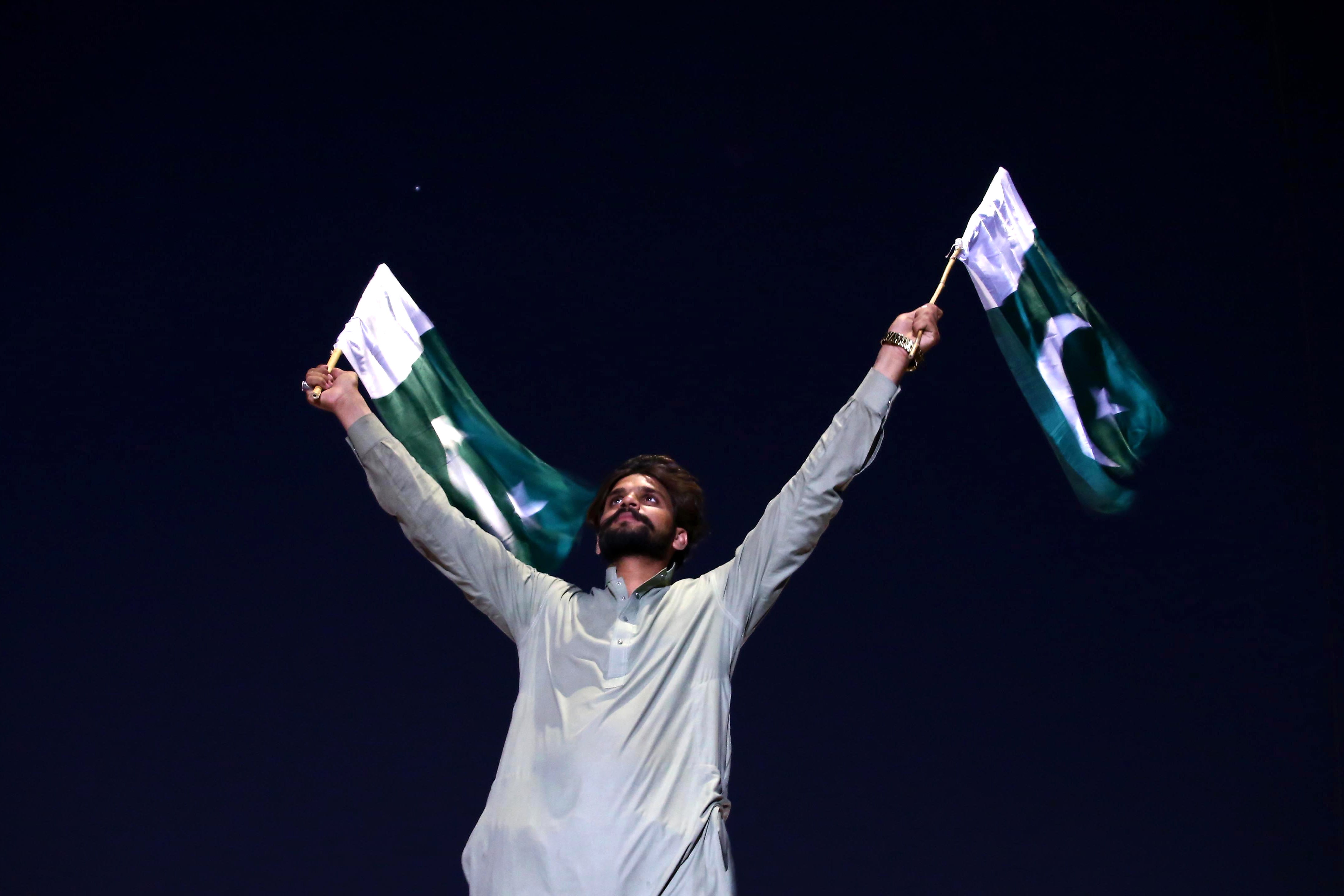 A man waves two Pakistani flags after a ceasefire was announced but fell through only hours after