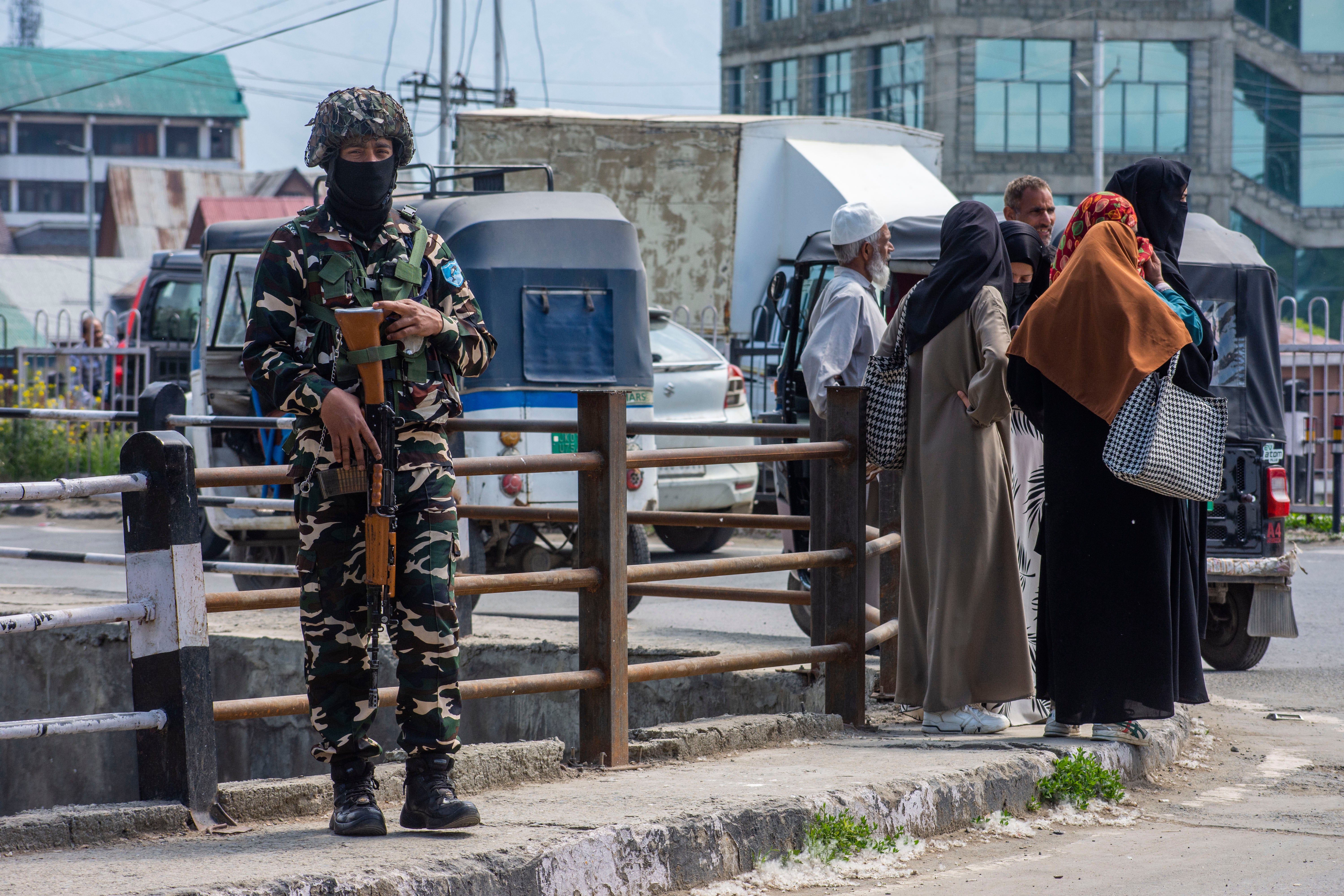 File. Kashmiri women wait for buses as an Indian paramilitary soldier stands on a road in Srinagar, Kashmir, on 26 April 2025
