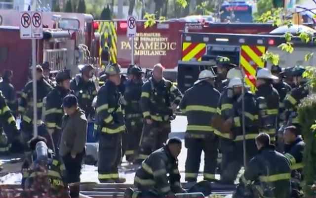 <p>Firefighters gather outside a Milwaukee apartment building that was engulfed in flames Sunday, killing four people and injuring dozens more </p>