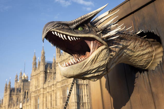 A 25-ft-long animatronic Hungarian Horntail dragon makes its way past Westminster (Matt Alexander/PA)