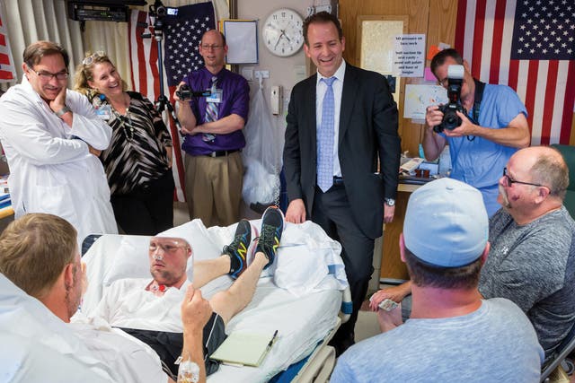 <p>Andy Sandness viewing his new face in the mirror during his recovery from a pioneering 56-hour operation at Mayo Clinic, Minnesota. The doctor who performed the surgery, Dr. Samir Mardini, is pictured at the foot of the bed</p>