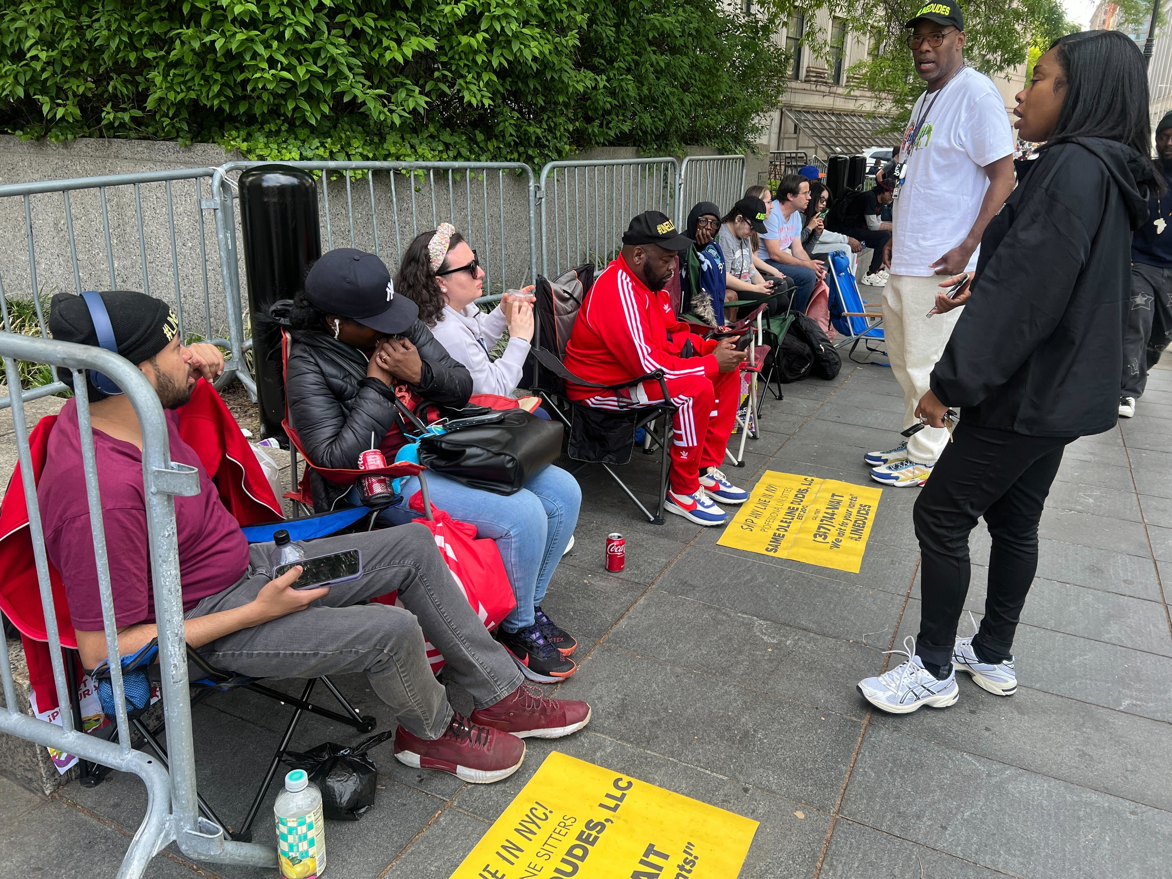 People hired by news outlets to hold a spot to get into court on Tuesday were already in line by 4 p.m. Monday.