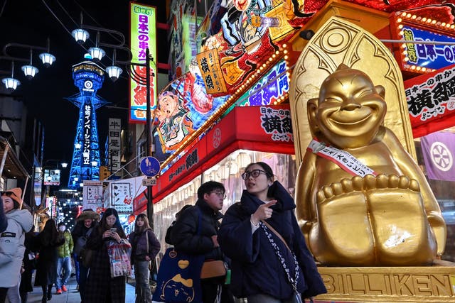 <p>File: Tourists walk past shops and restaurants in the popular Shinsekai district of Osaka</p>