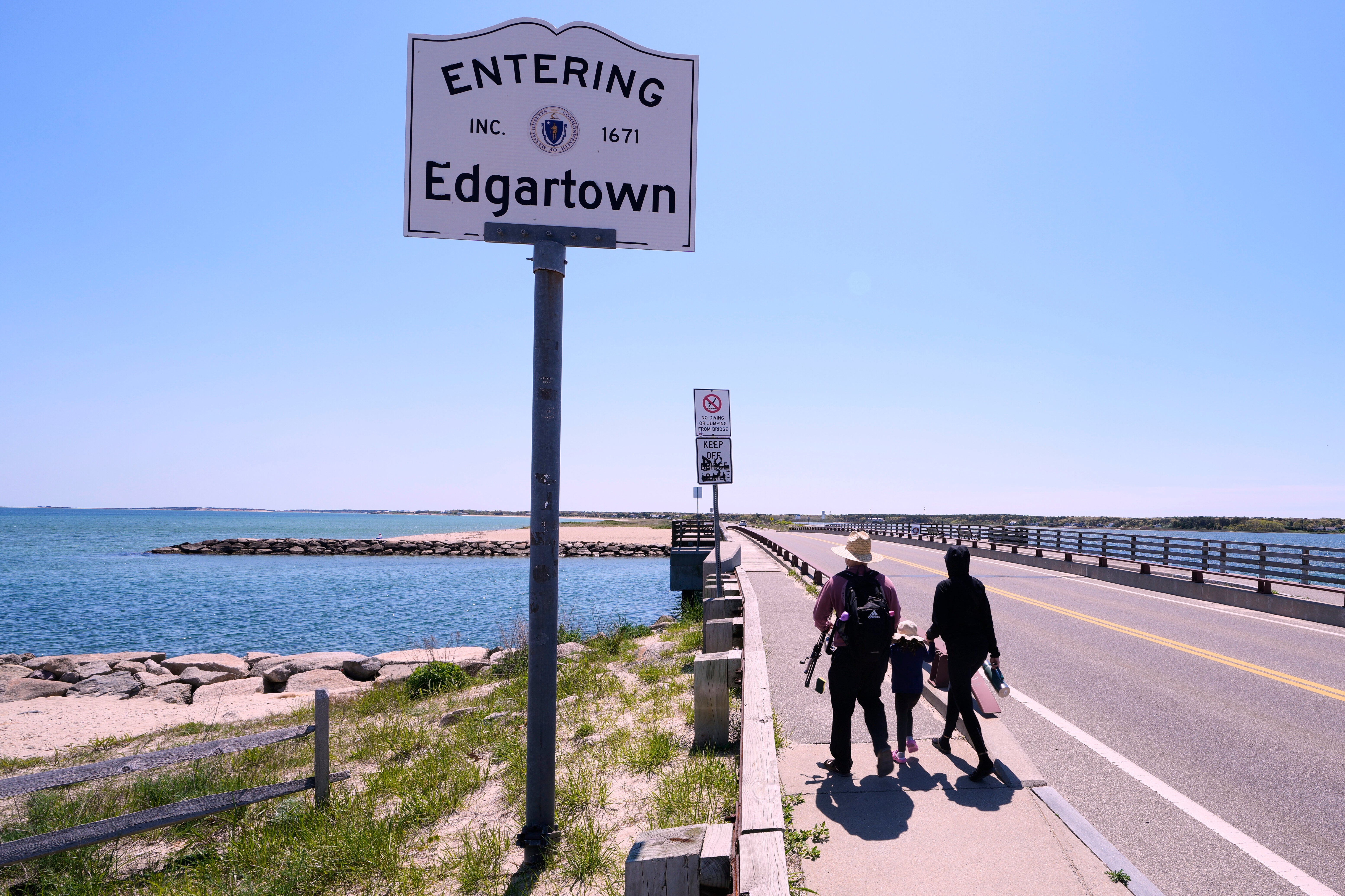 A family walks to the span of the American Legion Memorial Bridge, also known as the "Jaws Bridge", while spending the day fishing, Monday, May 12, 2025, in Edgartown, Mass., on Martha's Vineyard Island. (AP Photo/Charles Krupa)