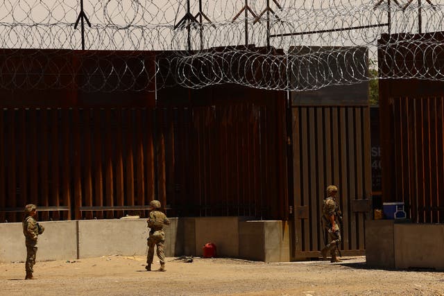 <p>U.S. military personnel stand near the wall on the U.S.-Mexico border</p>